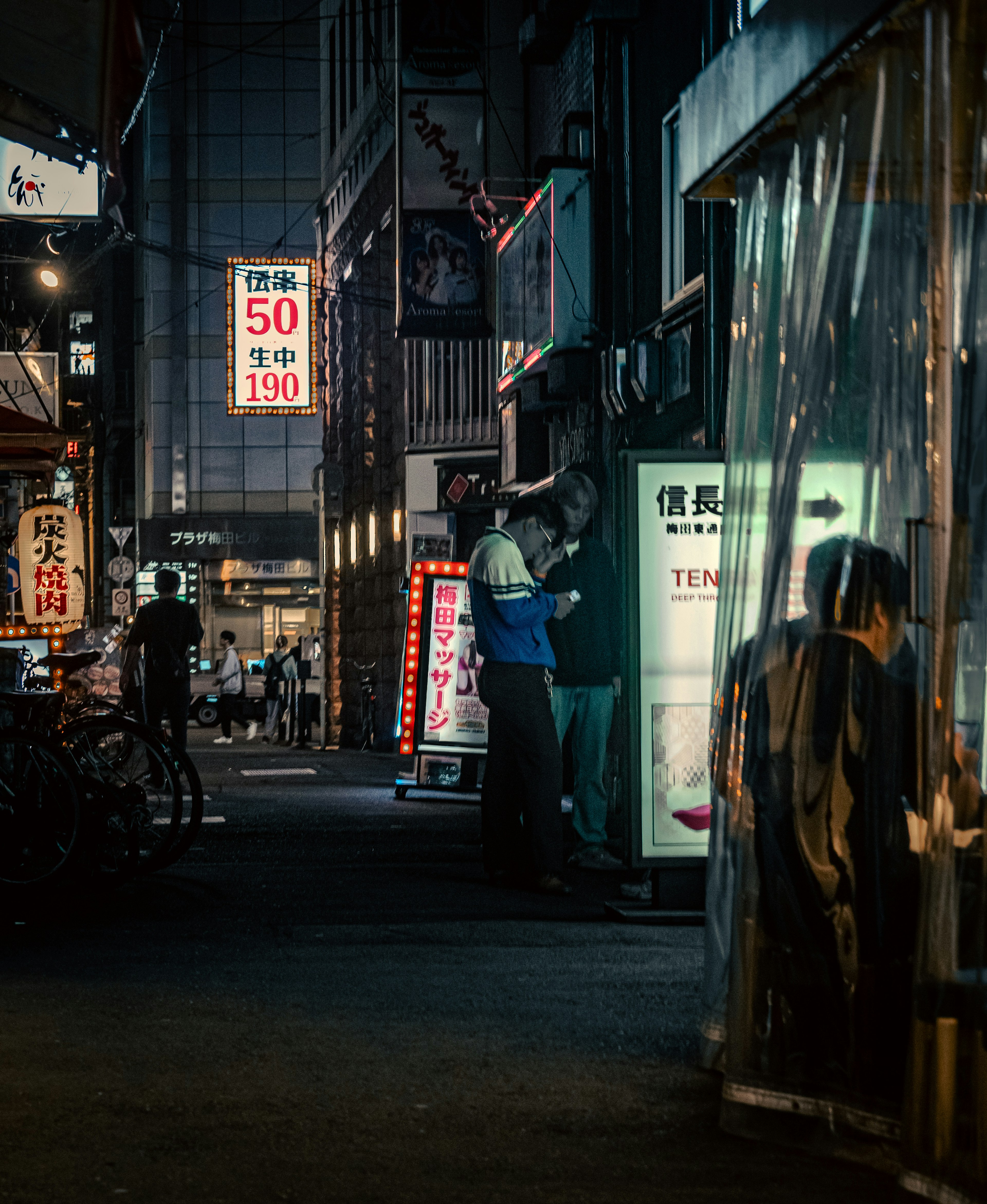 Night street scene featuring illuminated restaurant signs and people