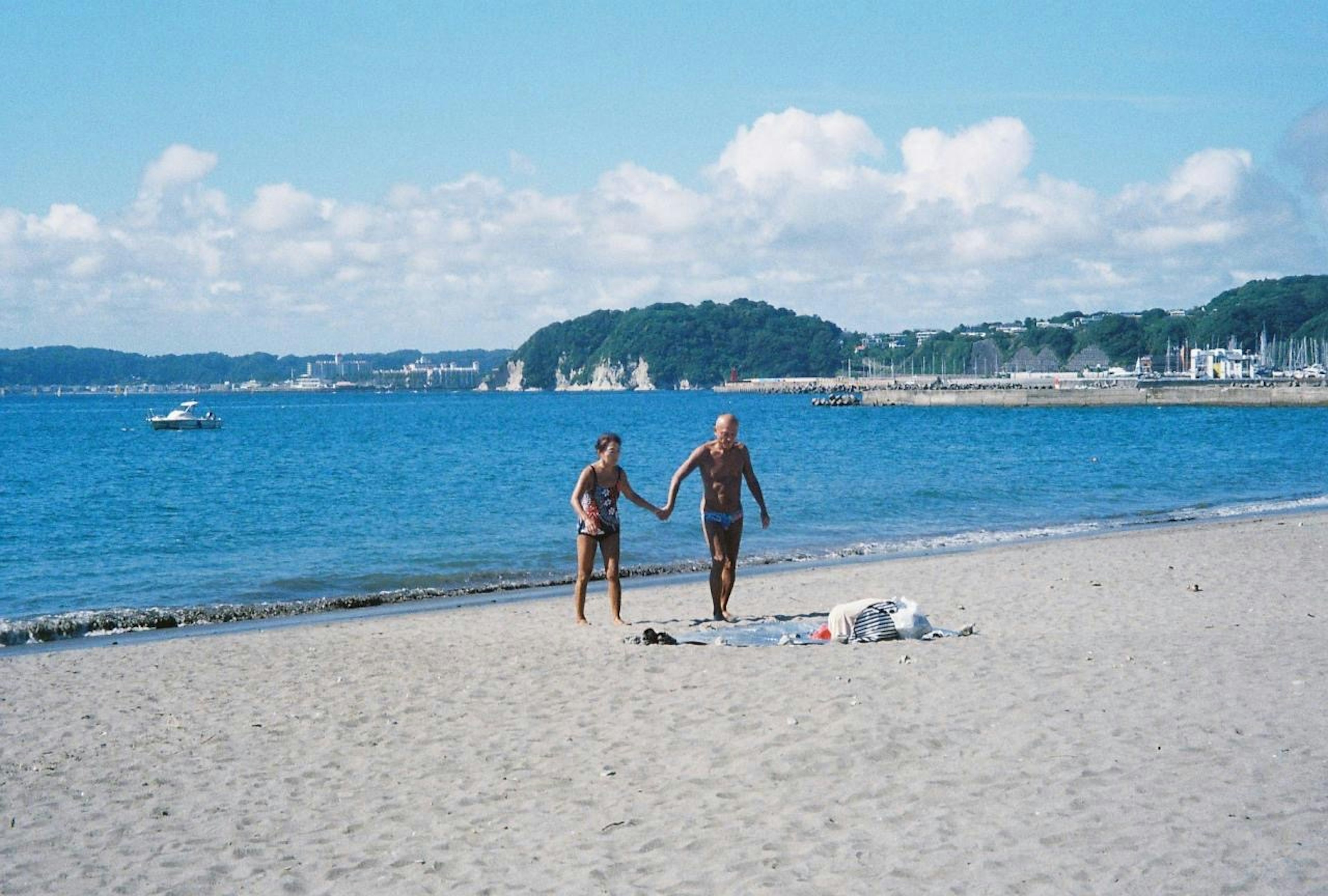 ビーチで手をつないで歩くカップル青い海と空