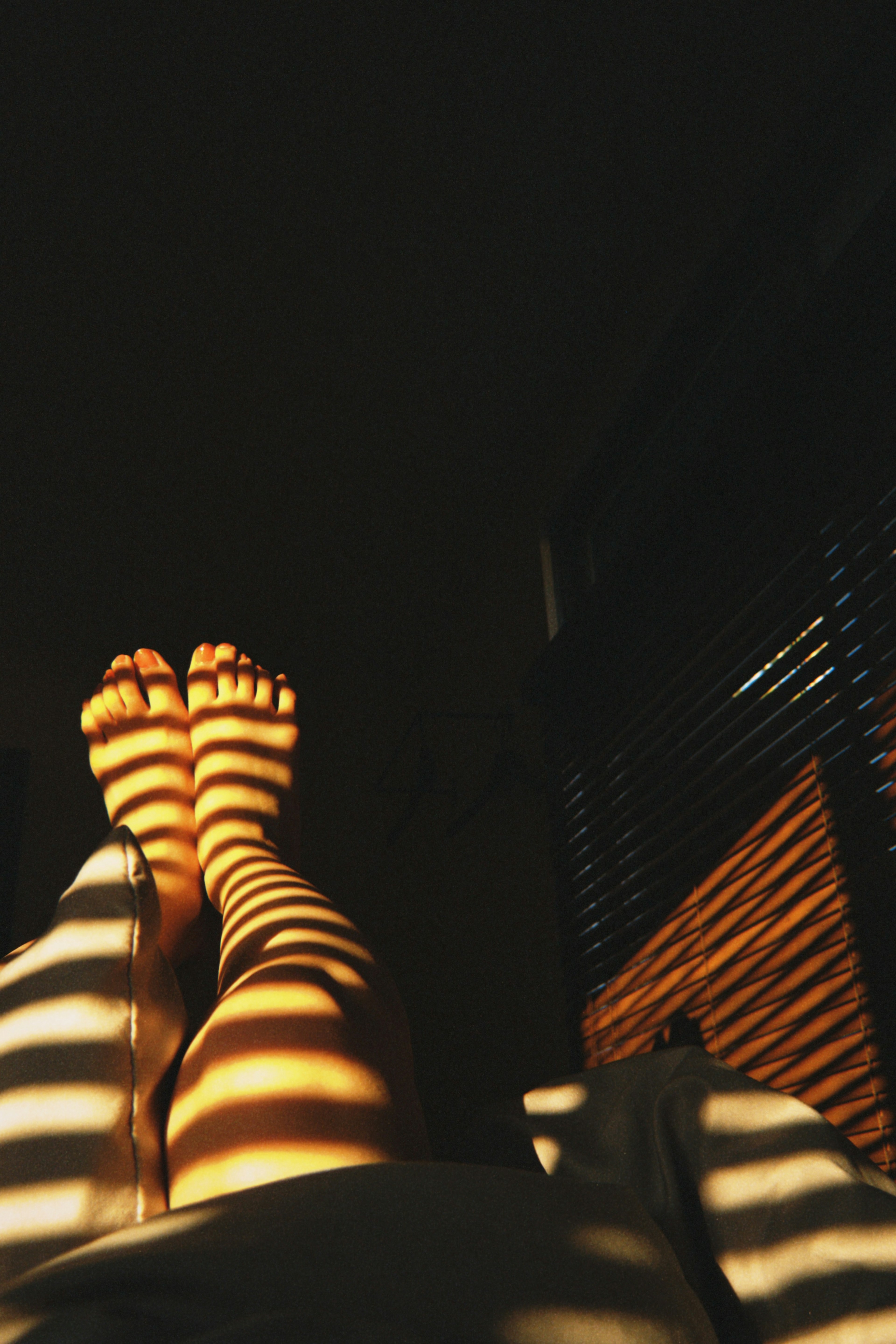 Feet resting on a surface with striped shadows