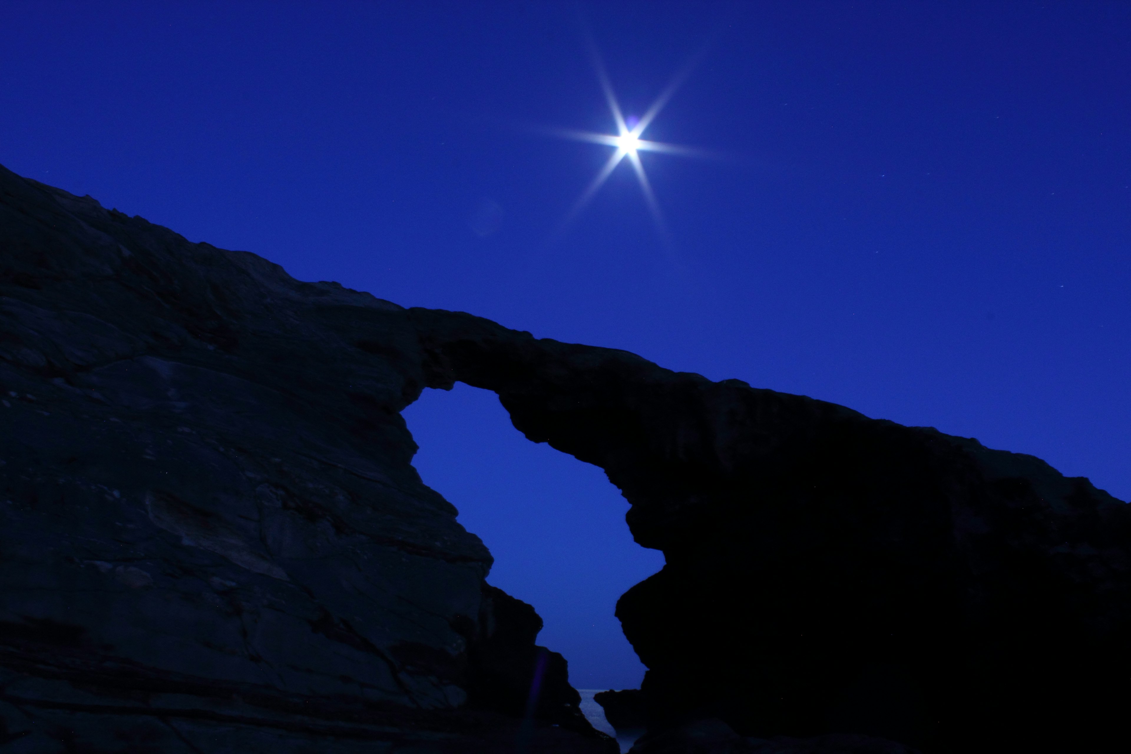 Étoile brillante dans le ciel nocturne au-dessus d'une arche de roche