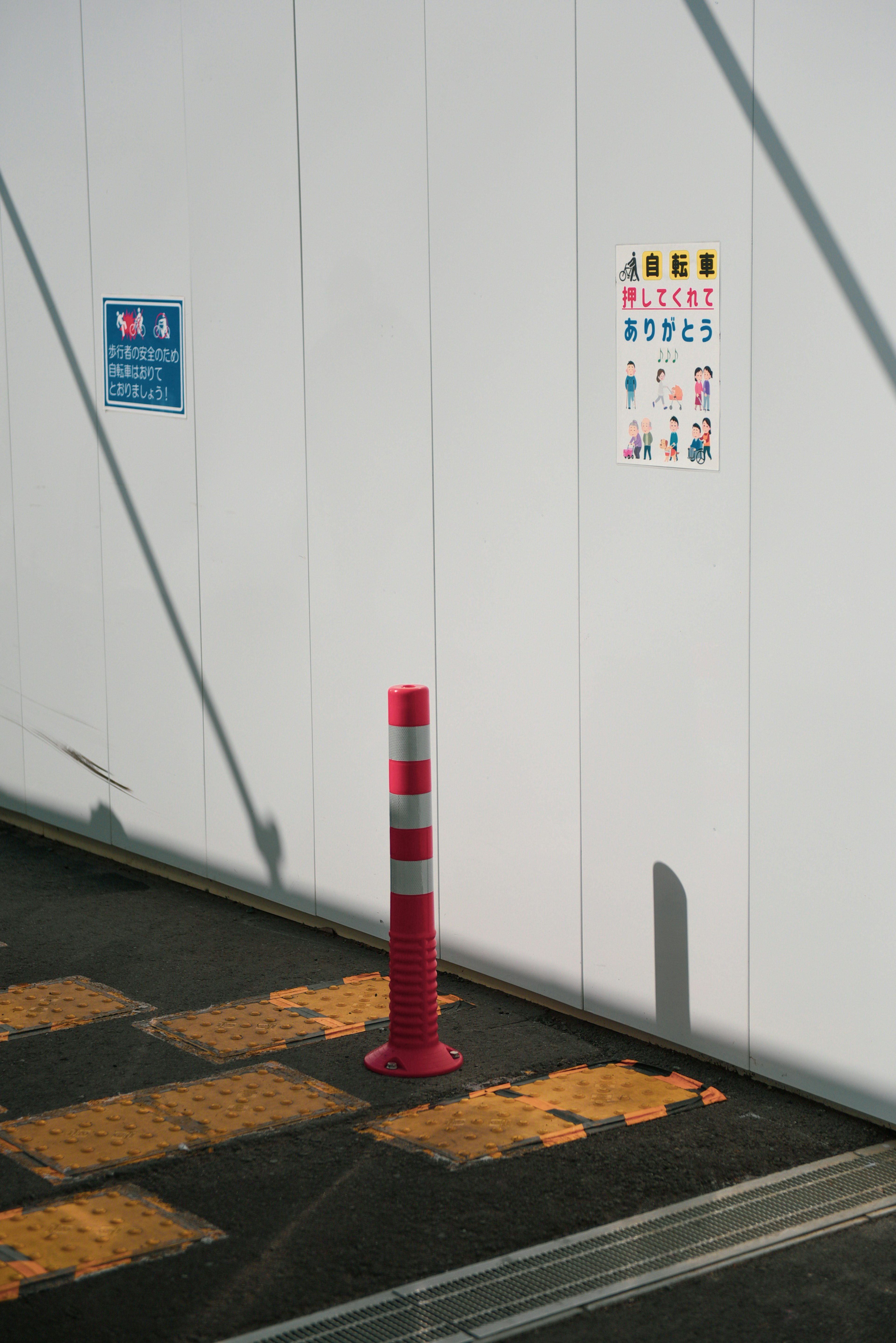 Red striped pole next to white wall with posted signs