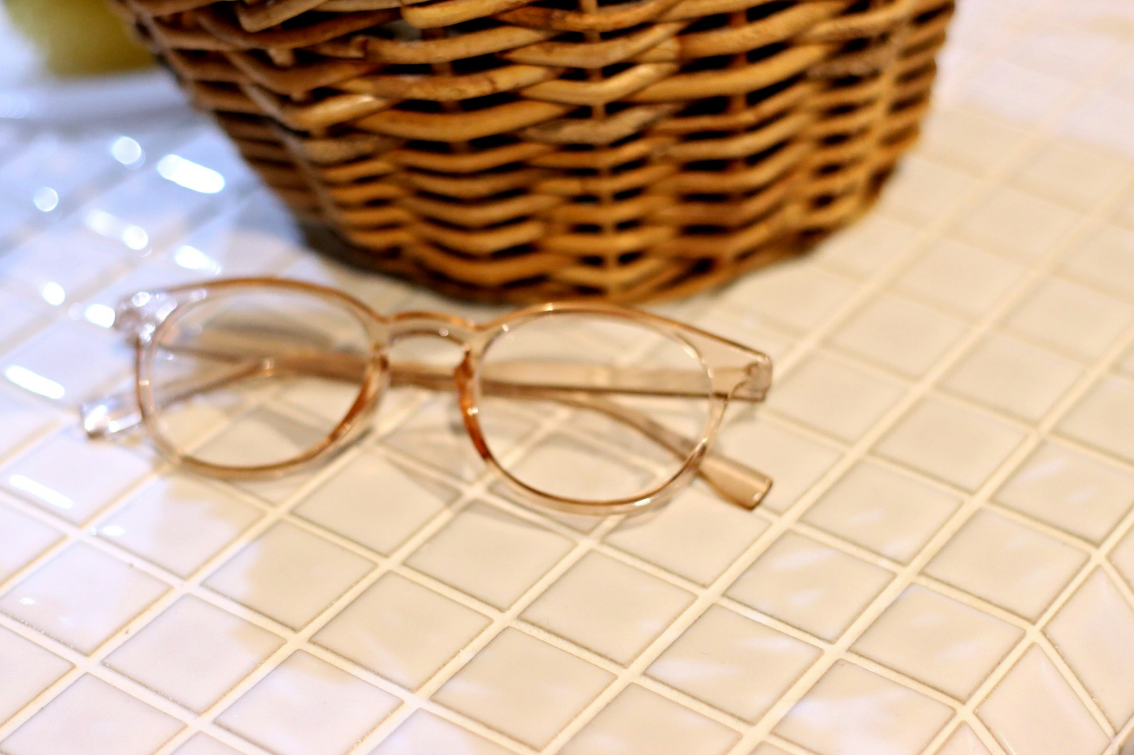 Gafas transparentes sobre una mesa texturizada junto a una cesta de mimbre