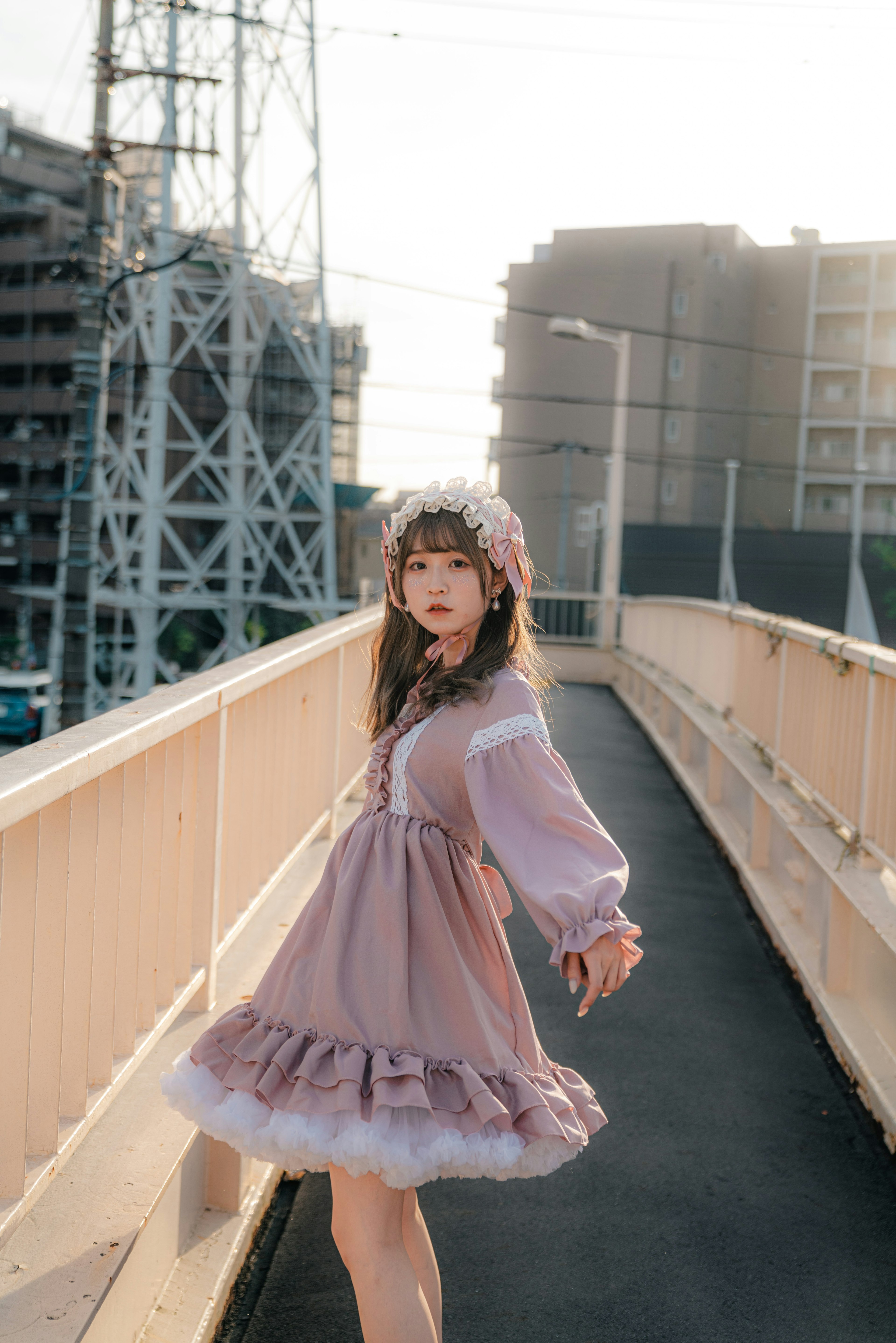 A girl in a cute pink dress posing on a bridge