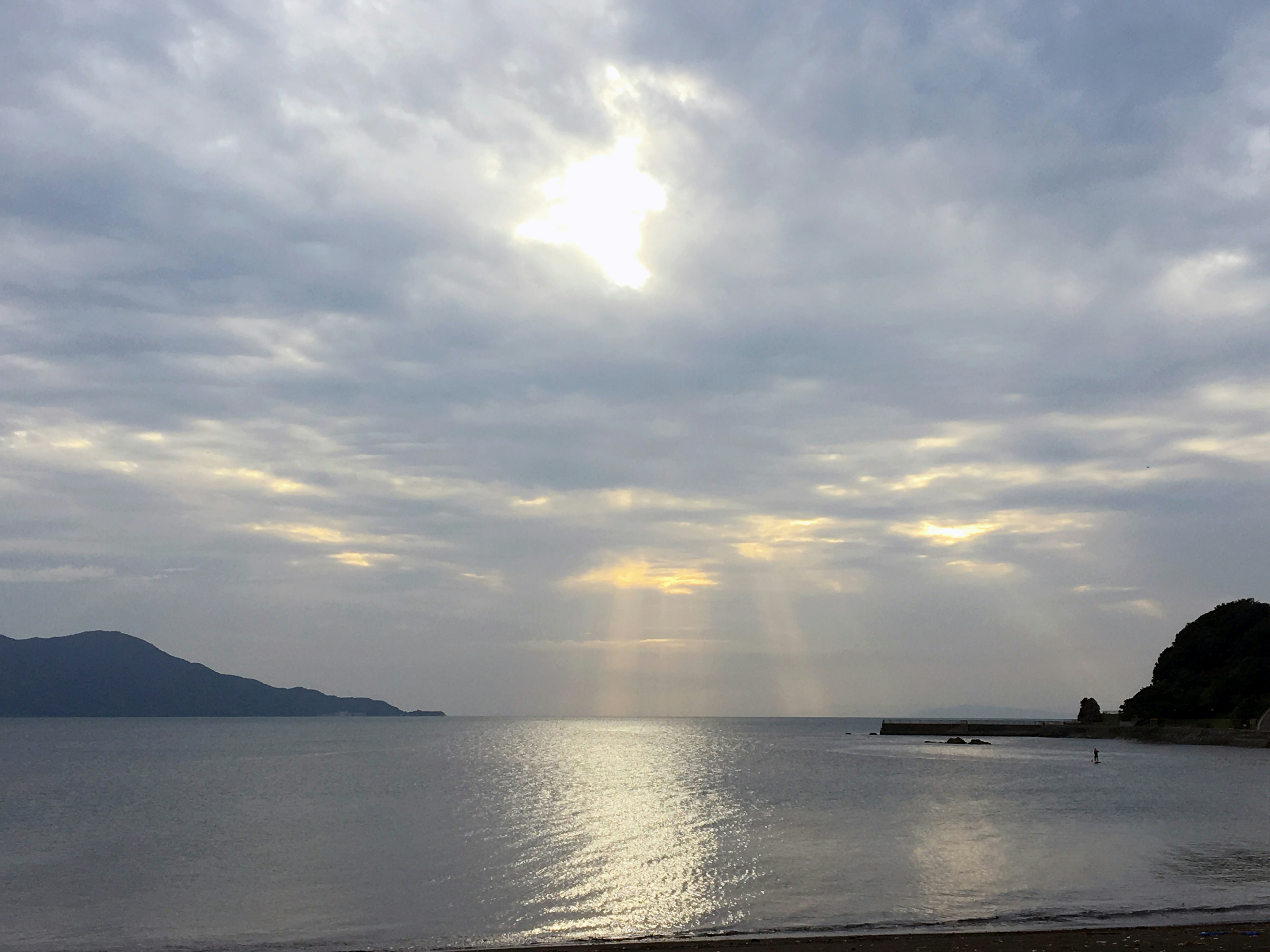 Ruhige Meereslandschaft mit bewölktem Himmel und Sonnenlicht, das sich im Wasser spiegelt