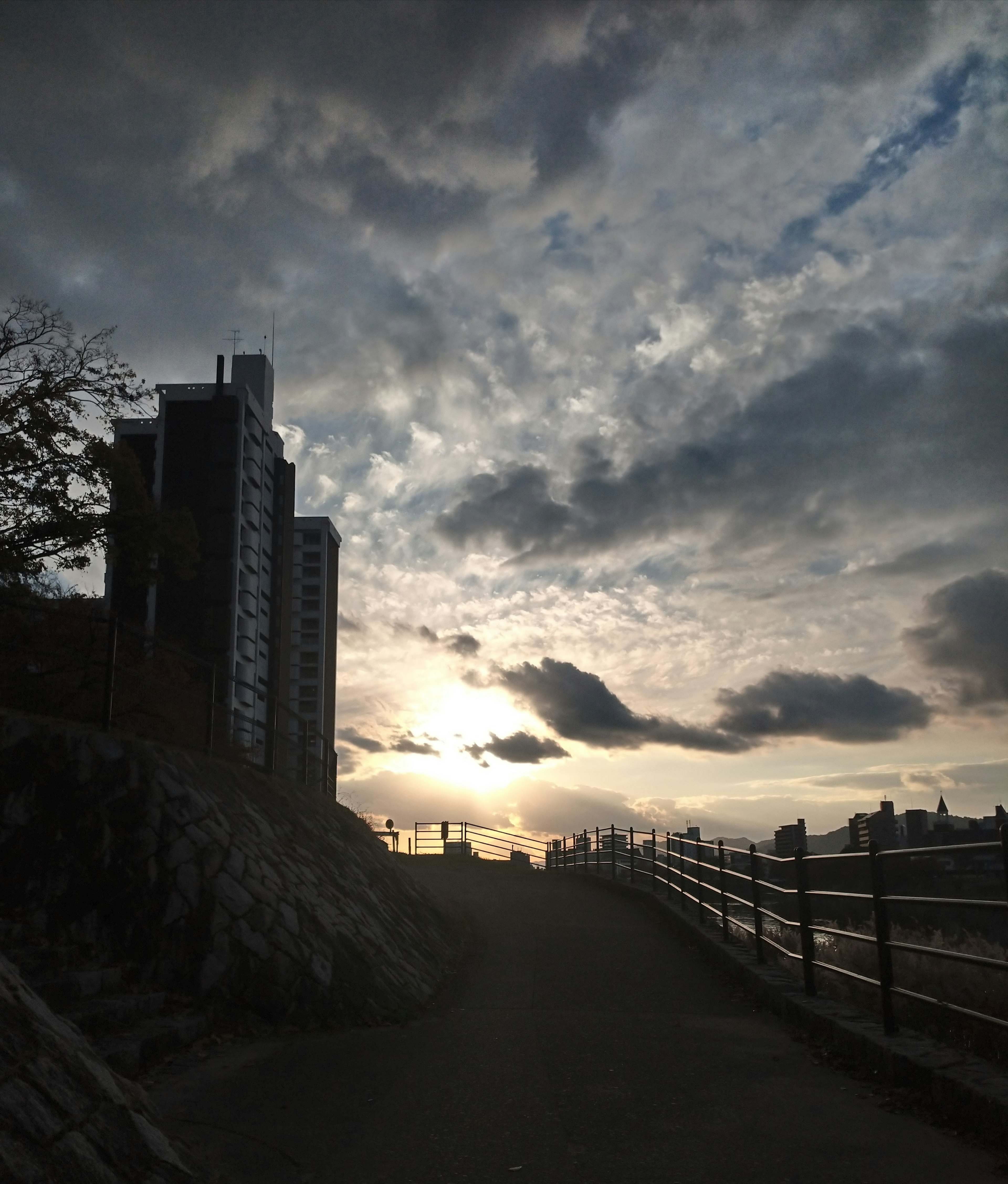 Silhouette eines Hochhauses gegen einen Sonnenuntergangshimmel entlang eines Weges