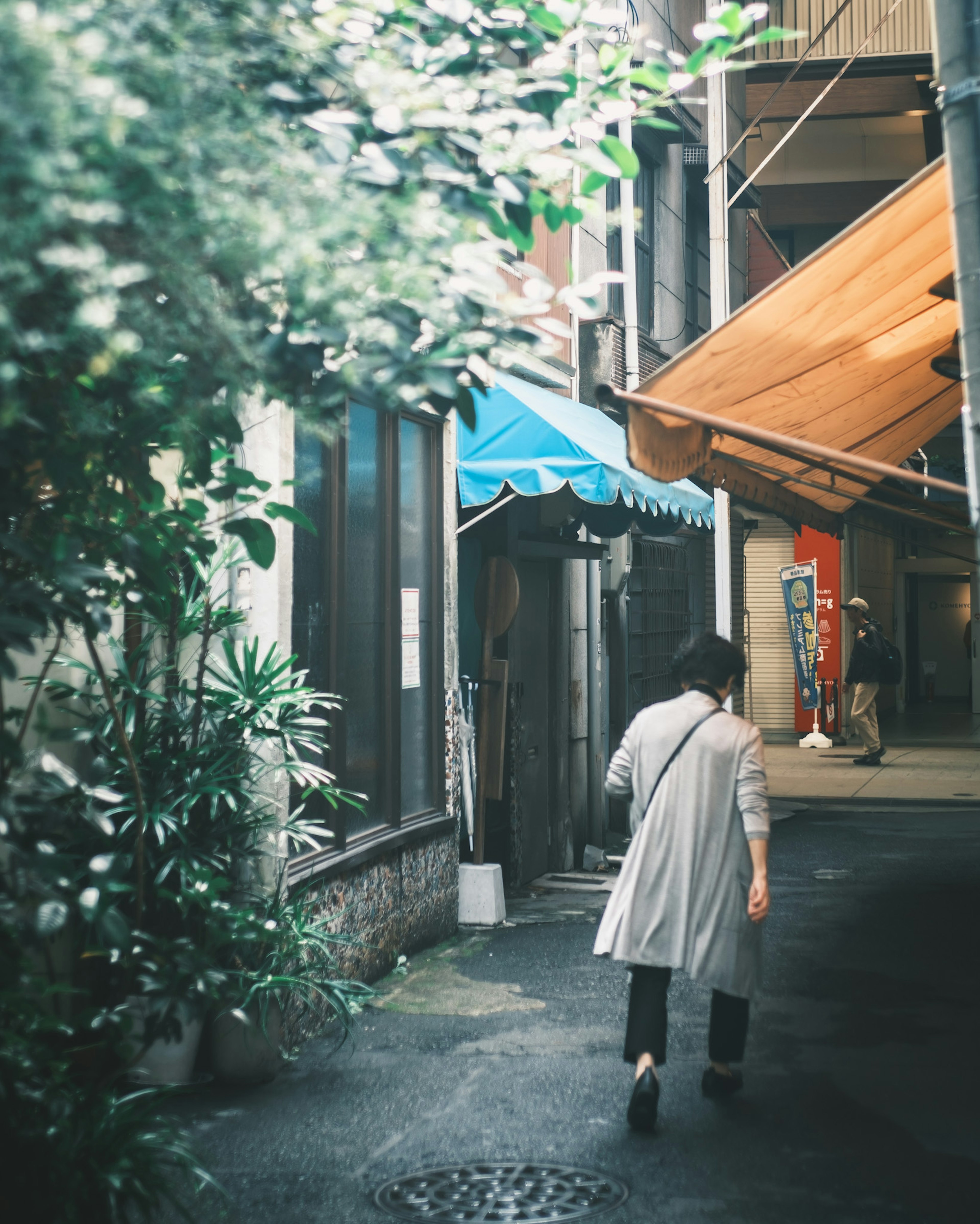 Woman walking down a narrow alley surrounded by greenery