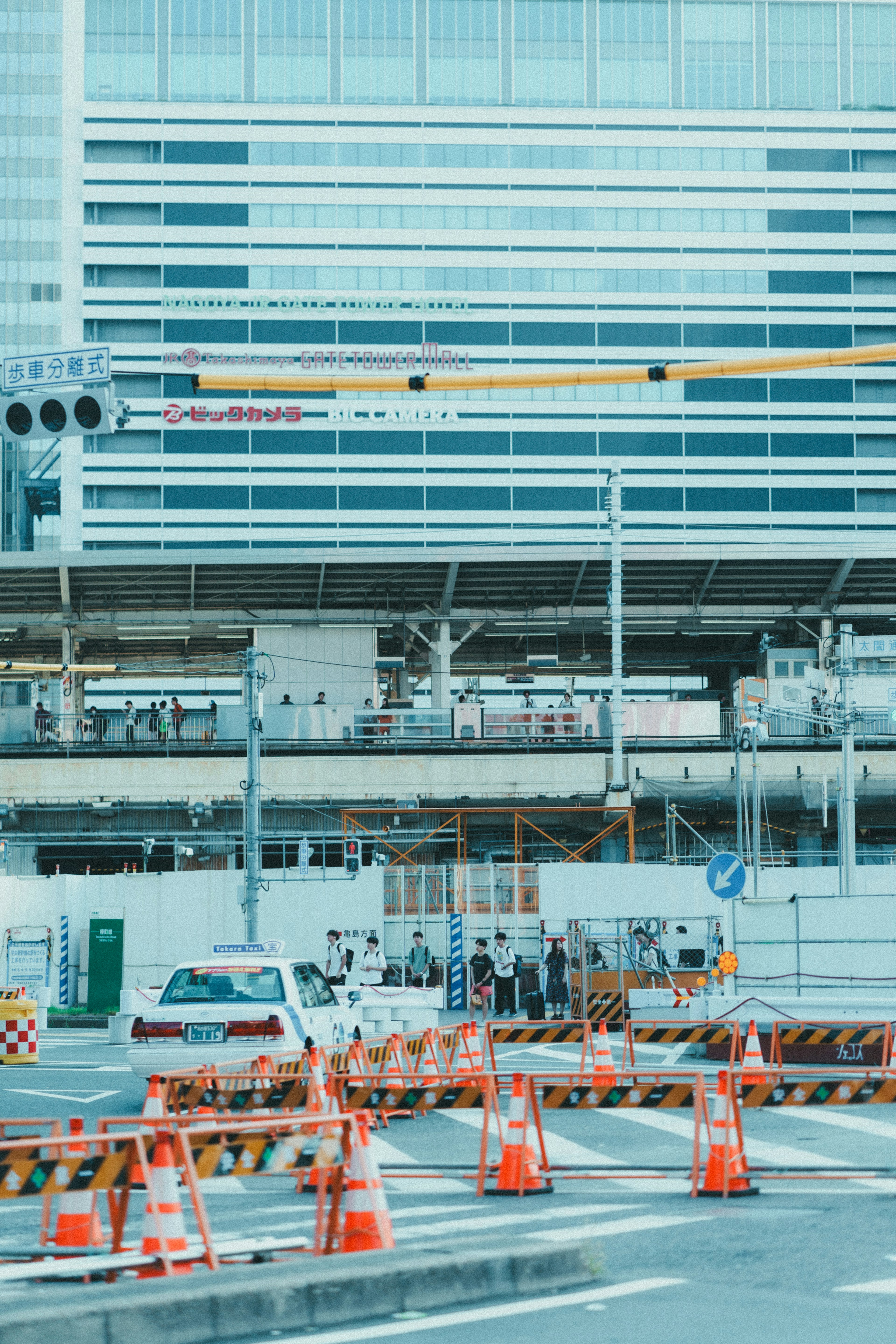 Baustelle mit orangefarbenen Absperrungen und einem modernen Gebäude