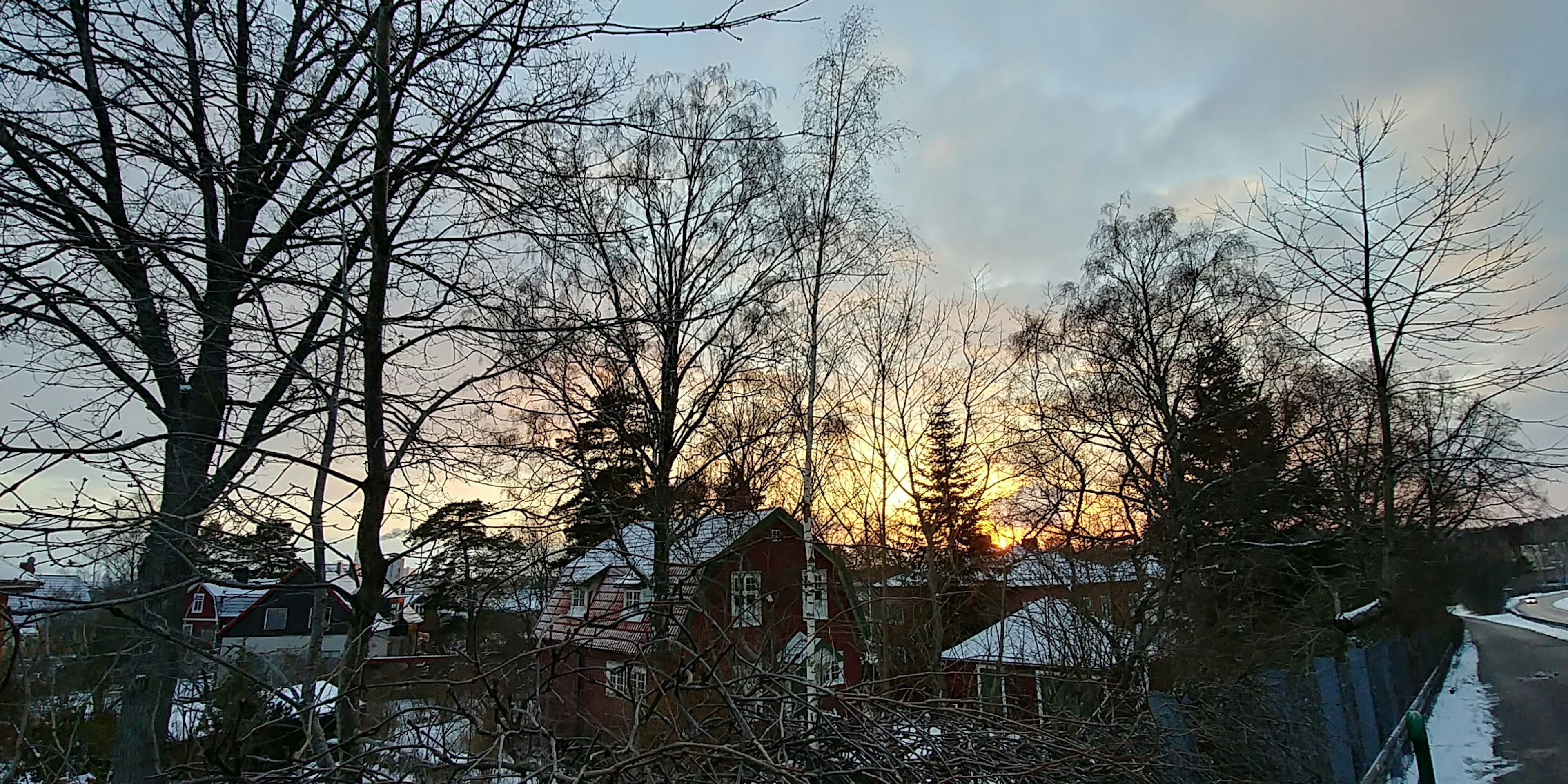 Snow-covered houses and trees silhouetted against a winter sunset