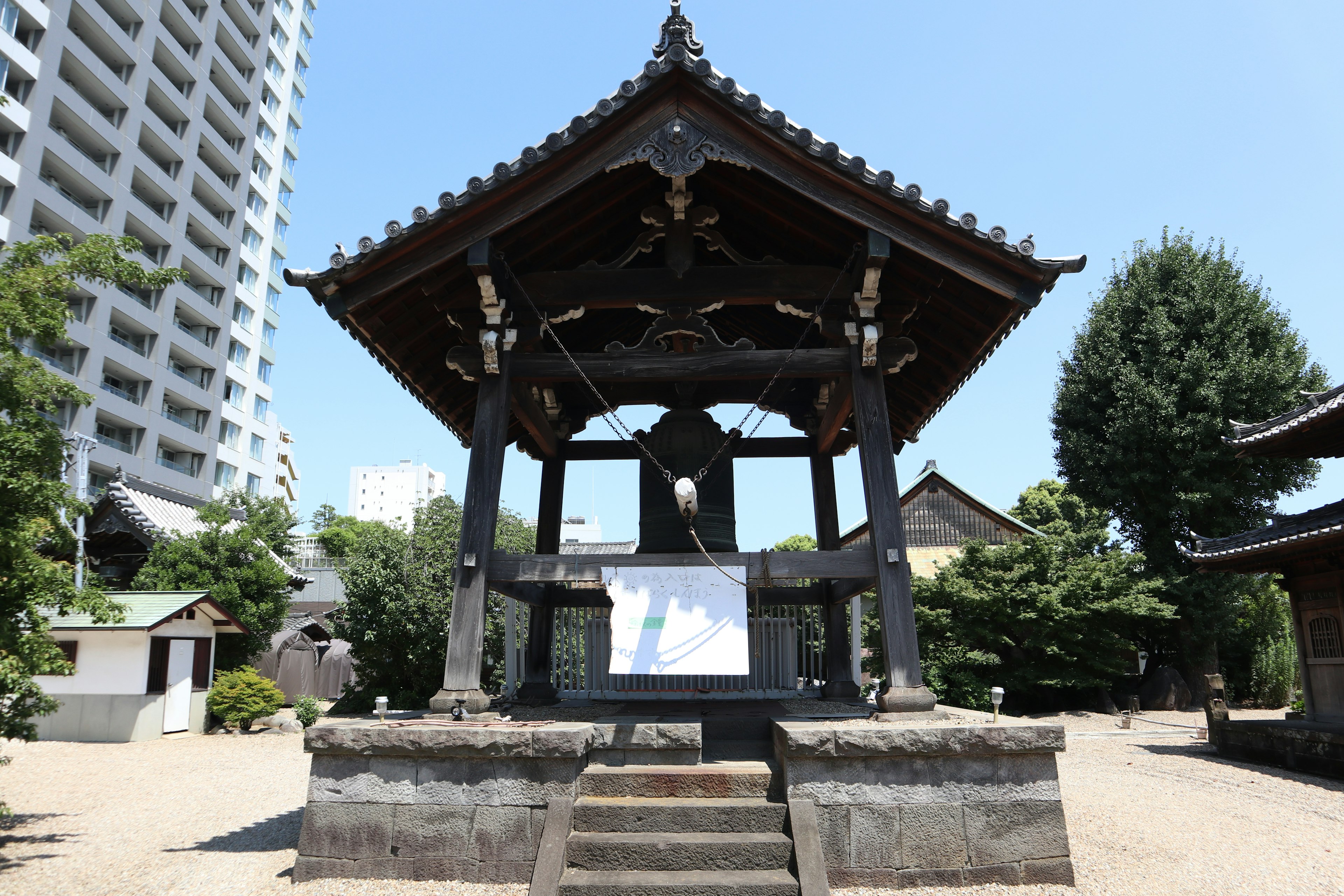 Traditional Japanese bell tower next to a modern high-rise building