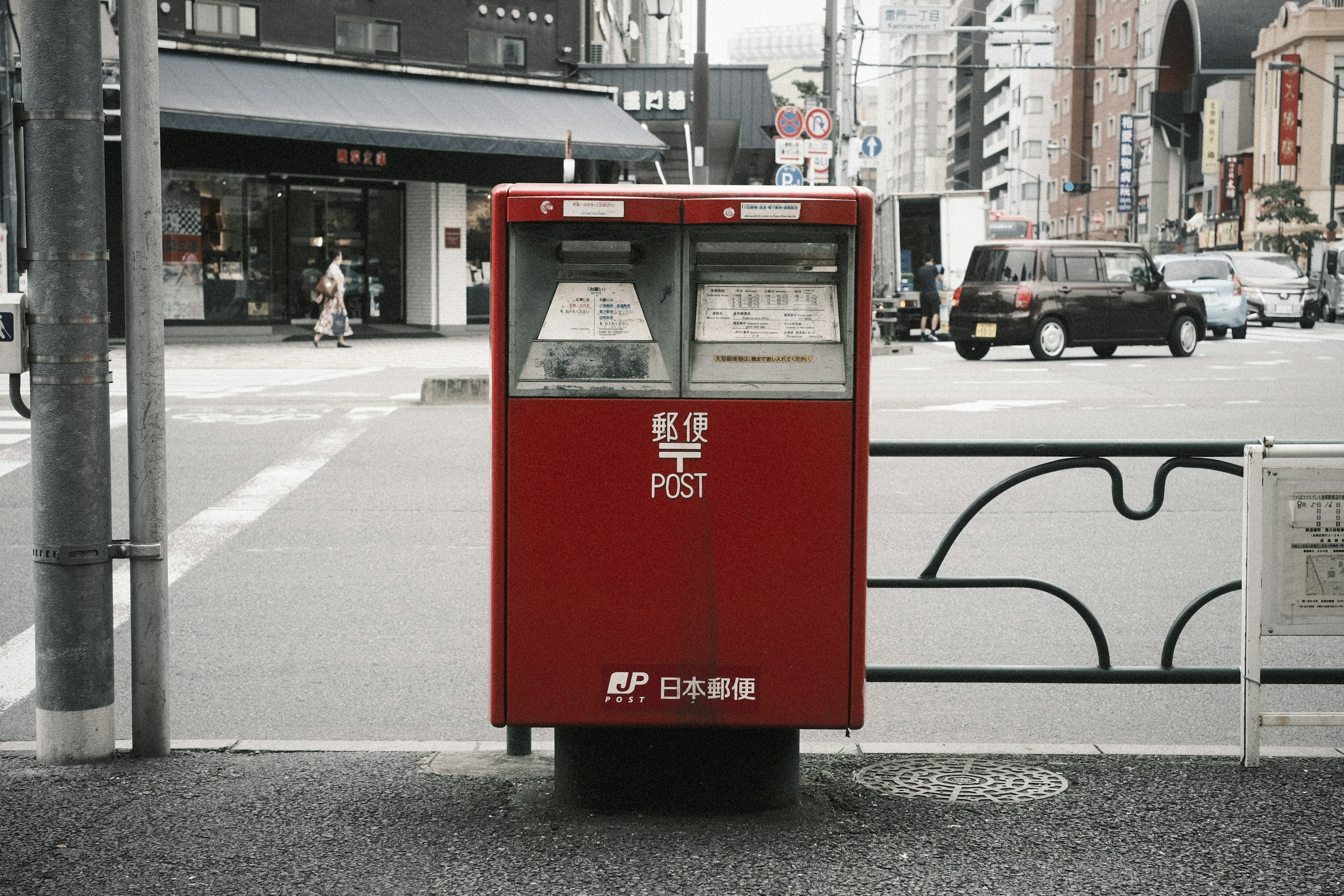 A red mailbox stands at a street corner