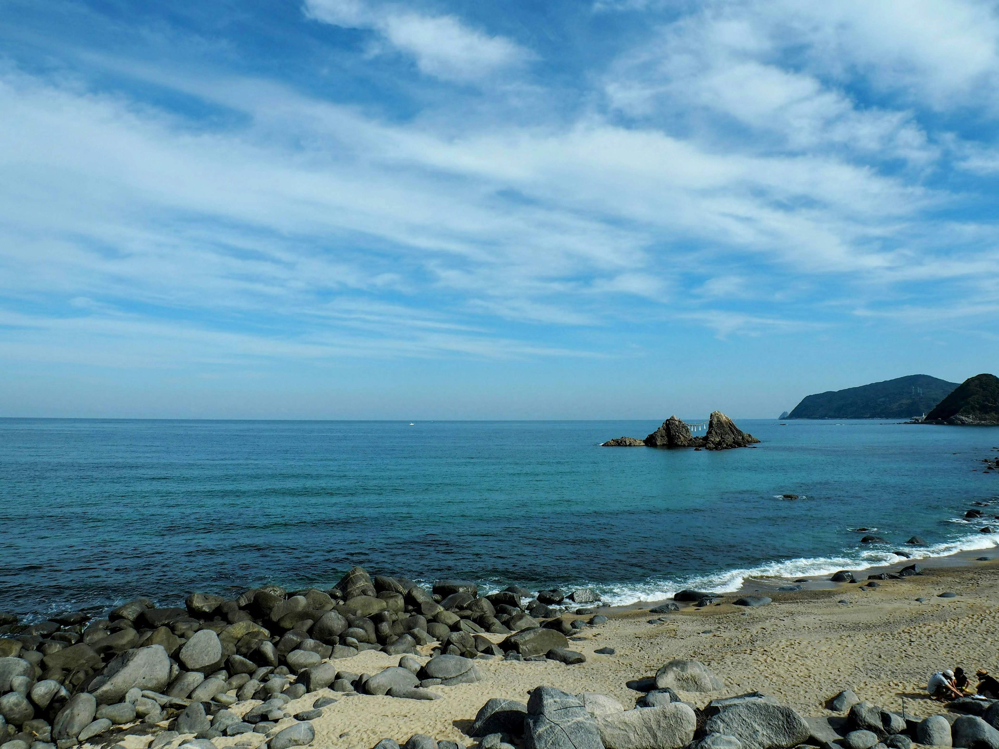 ทิวทัศน์ที่สวยงามของทะเลและท้องฟ้าสีฟ้าพร้อมชายหาดหิน