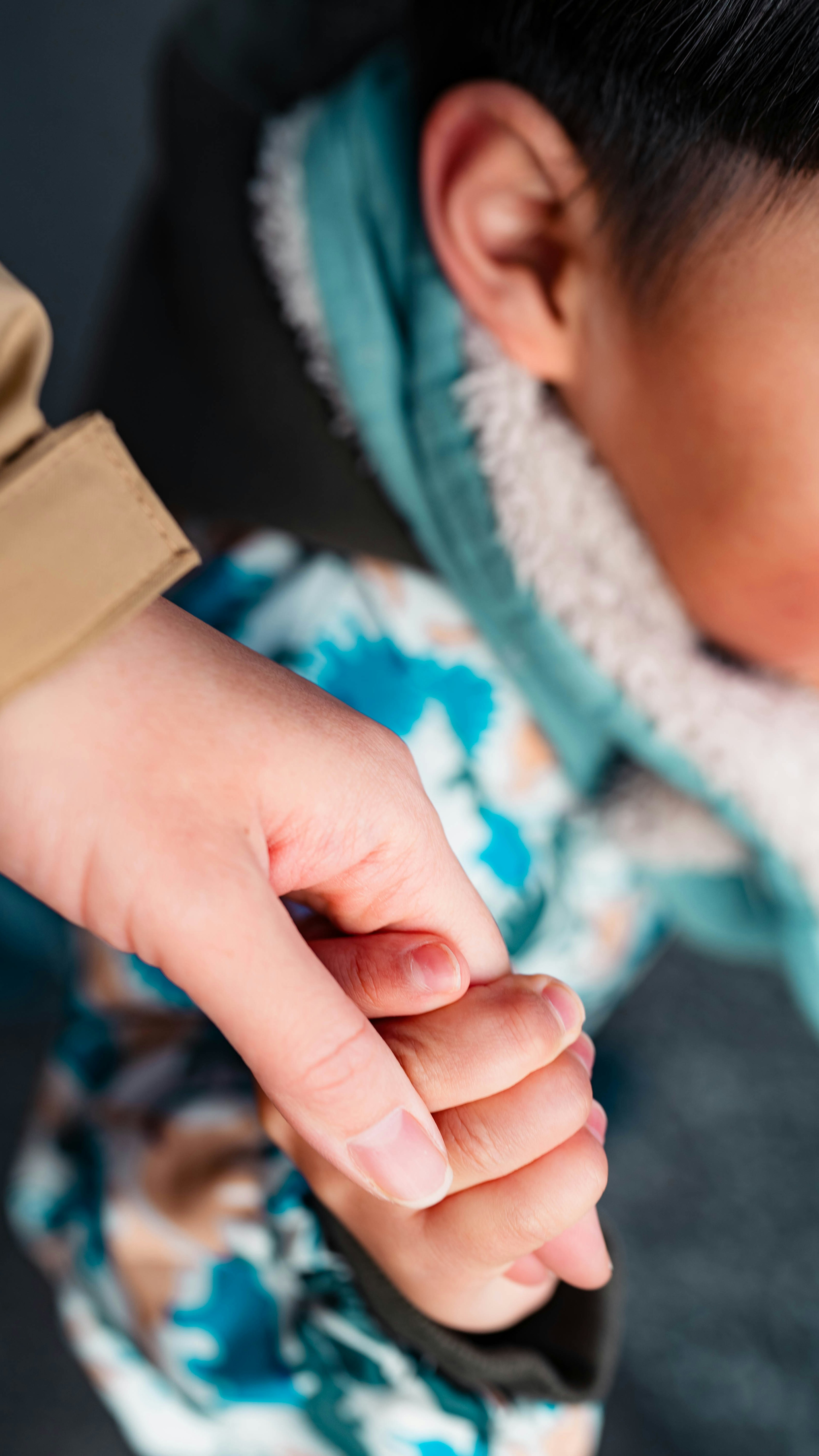 Close-up photo of a child and adult holding hands