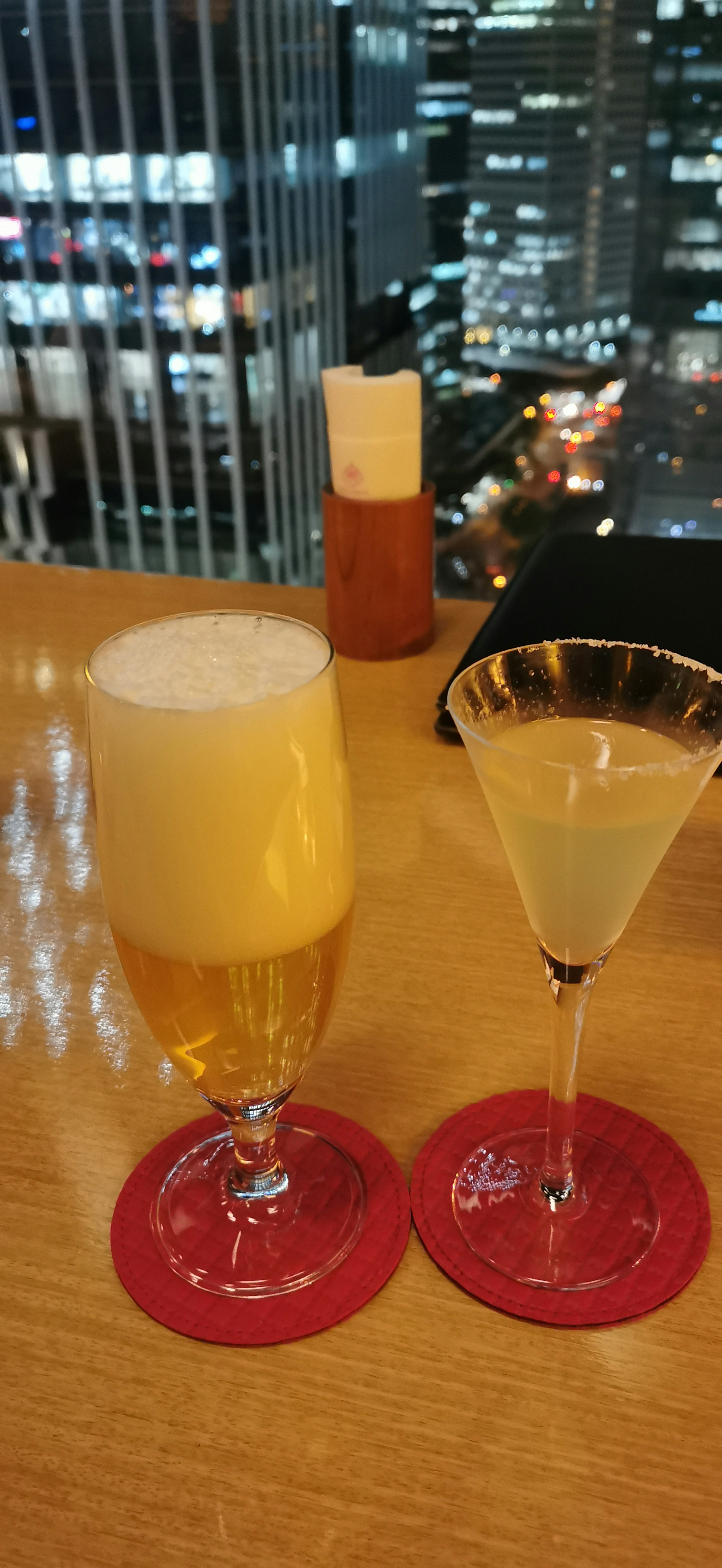 Two drinks with a city skyline backdrop and red coasters