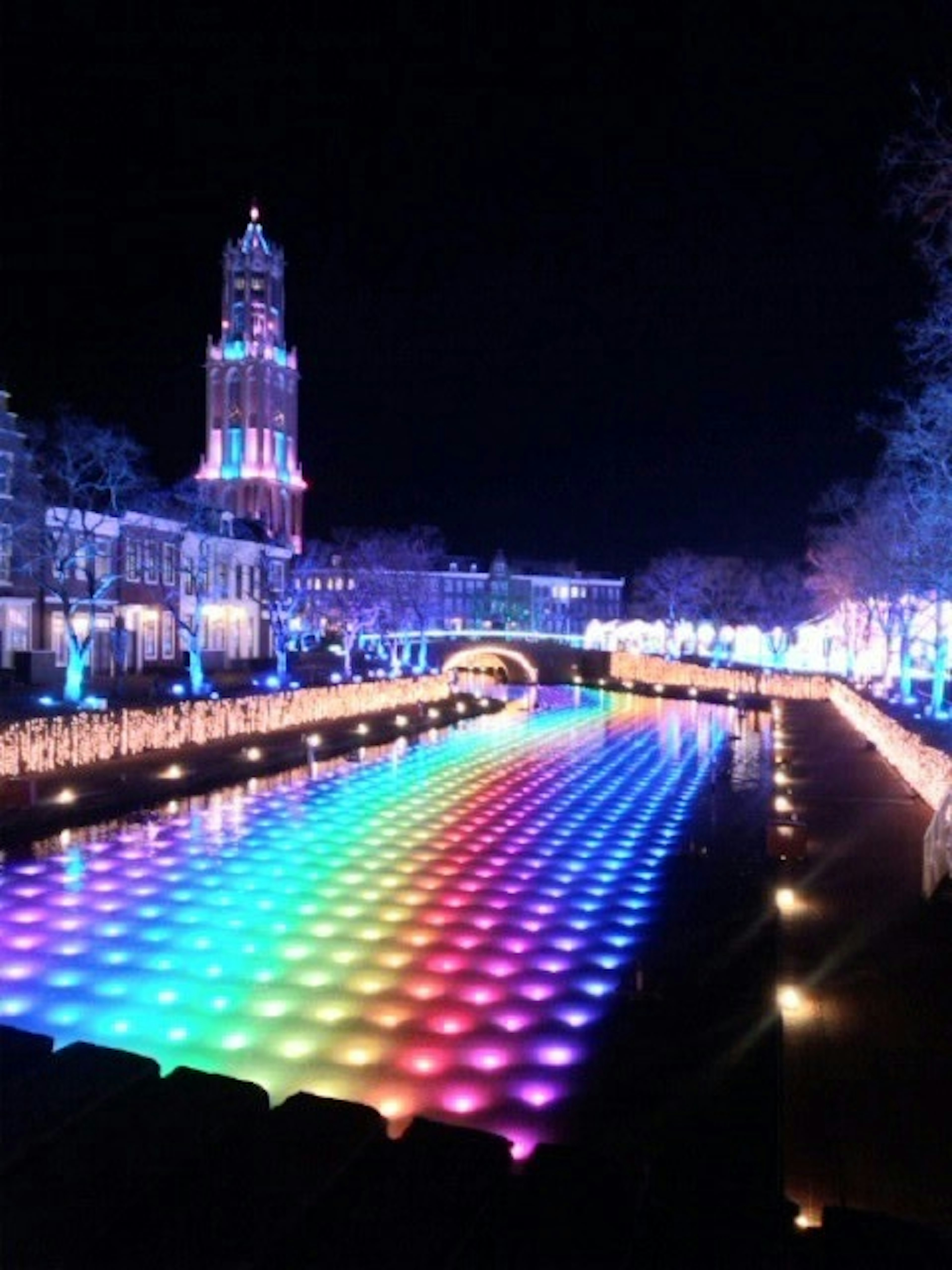 Colorful light patterns reflected on the river at night with historical buildings