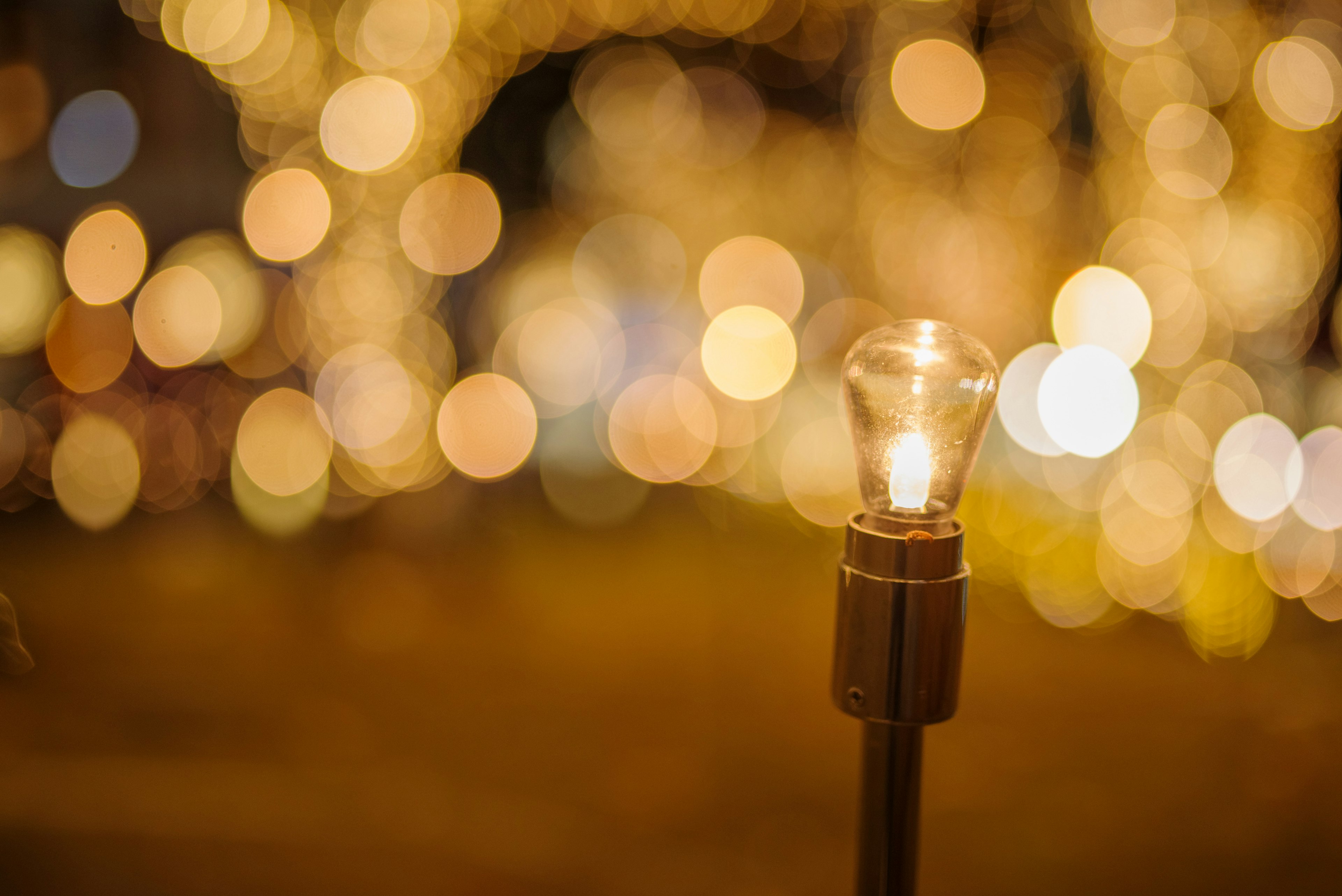 Una lampadina luminosa in primo piano con uno sfondo sfocato di luci calde