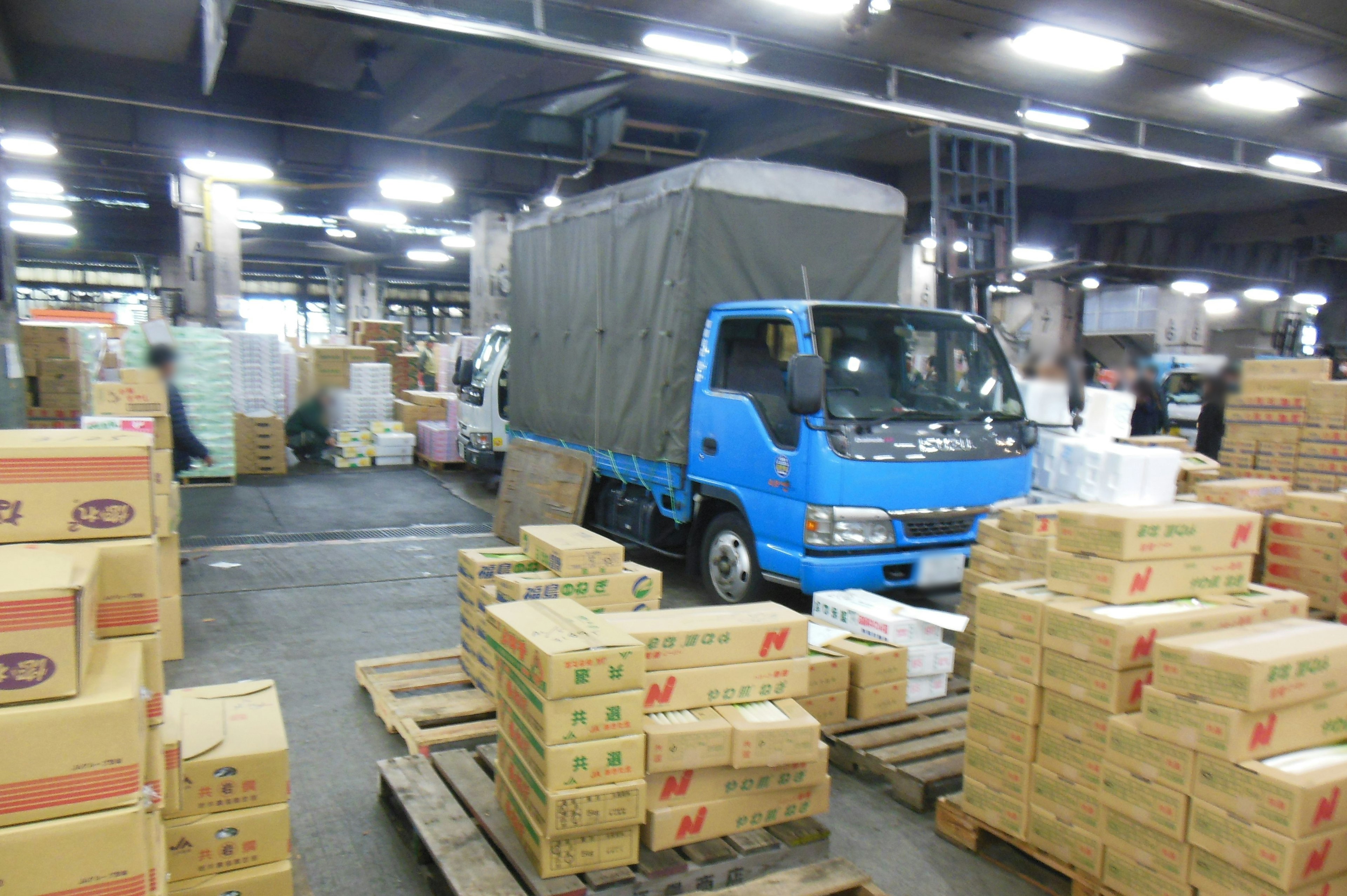 Interior of a warehouse with a blue truck surrounded by boxes