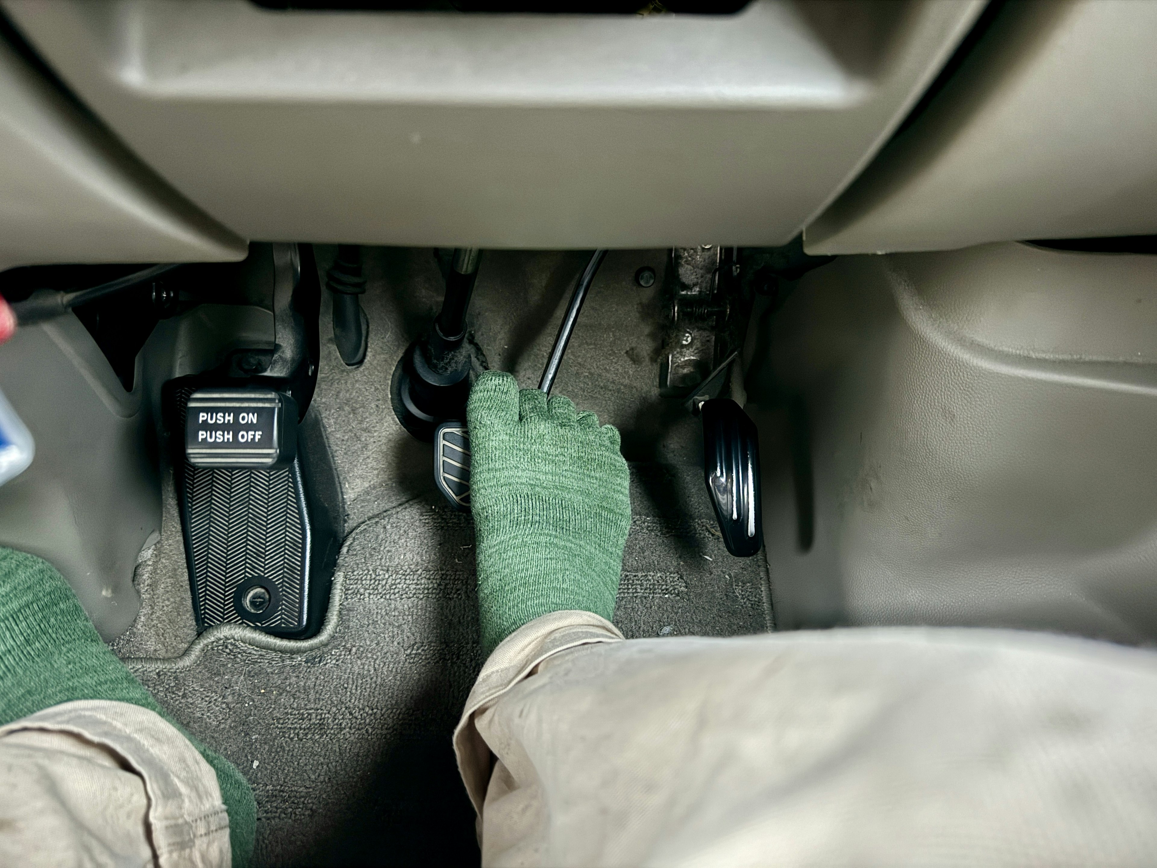 Feet in green socks positioned on the pedals inside a vehicle