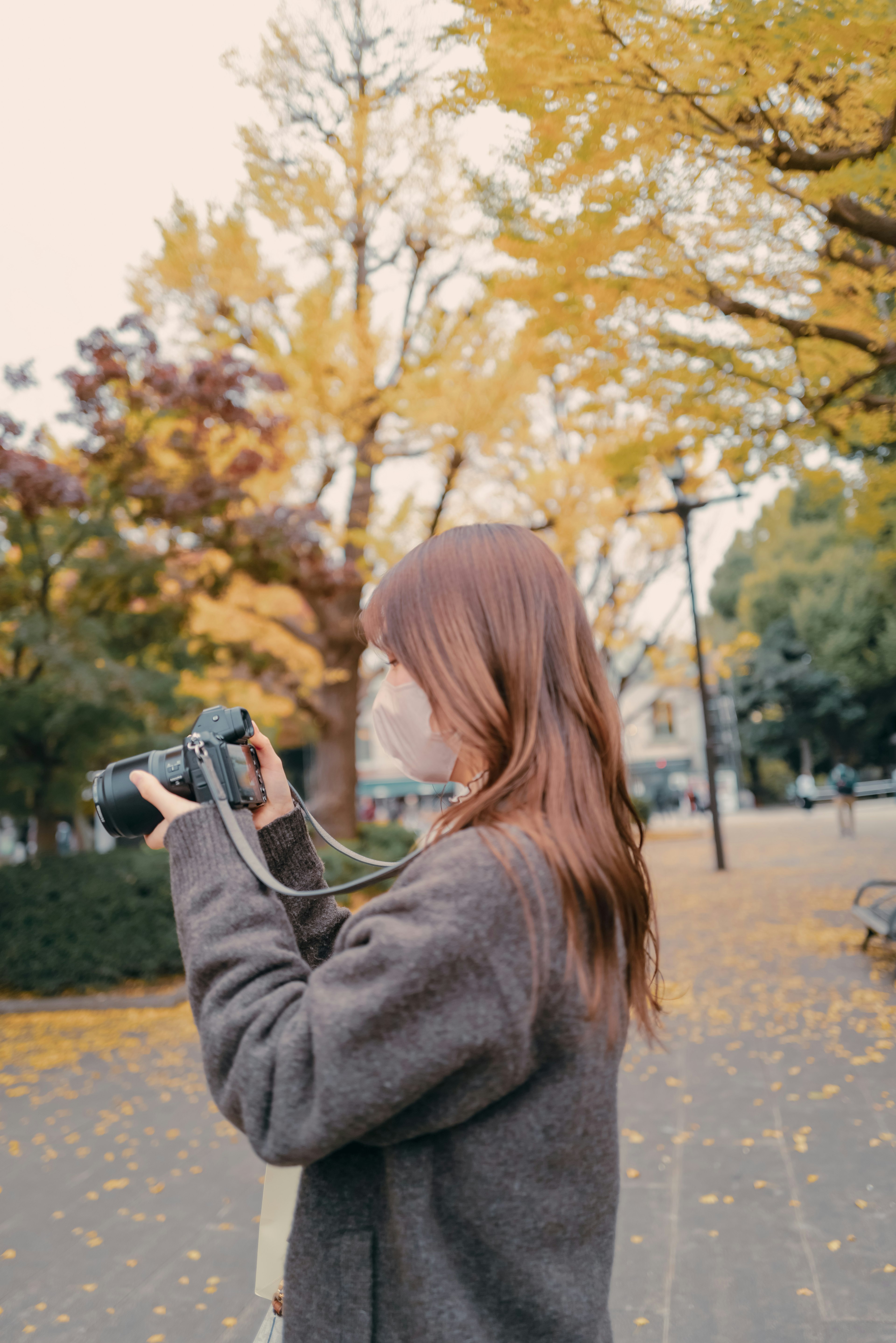 Perfil de una mujer sosteniendo una cámara en un parque de otoño