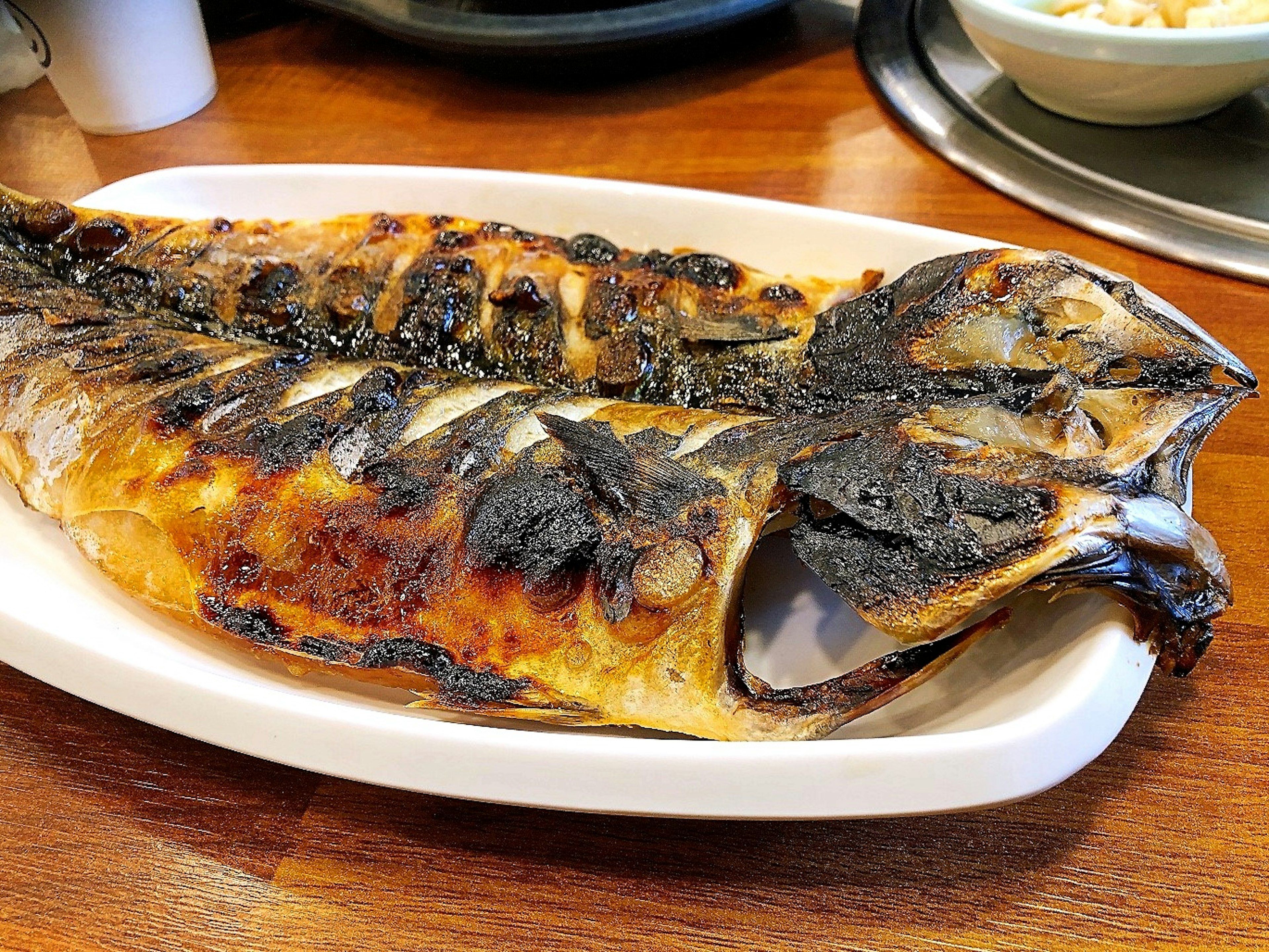 Large grilled fish served on a white plate