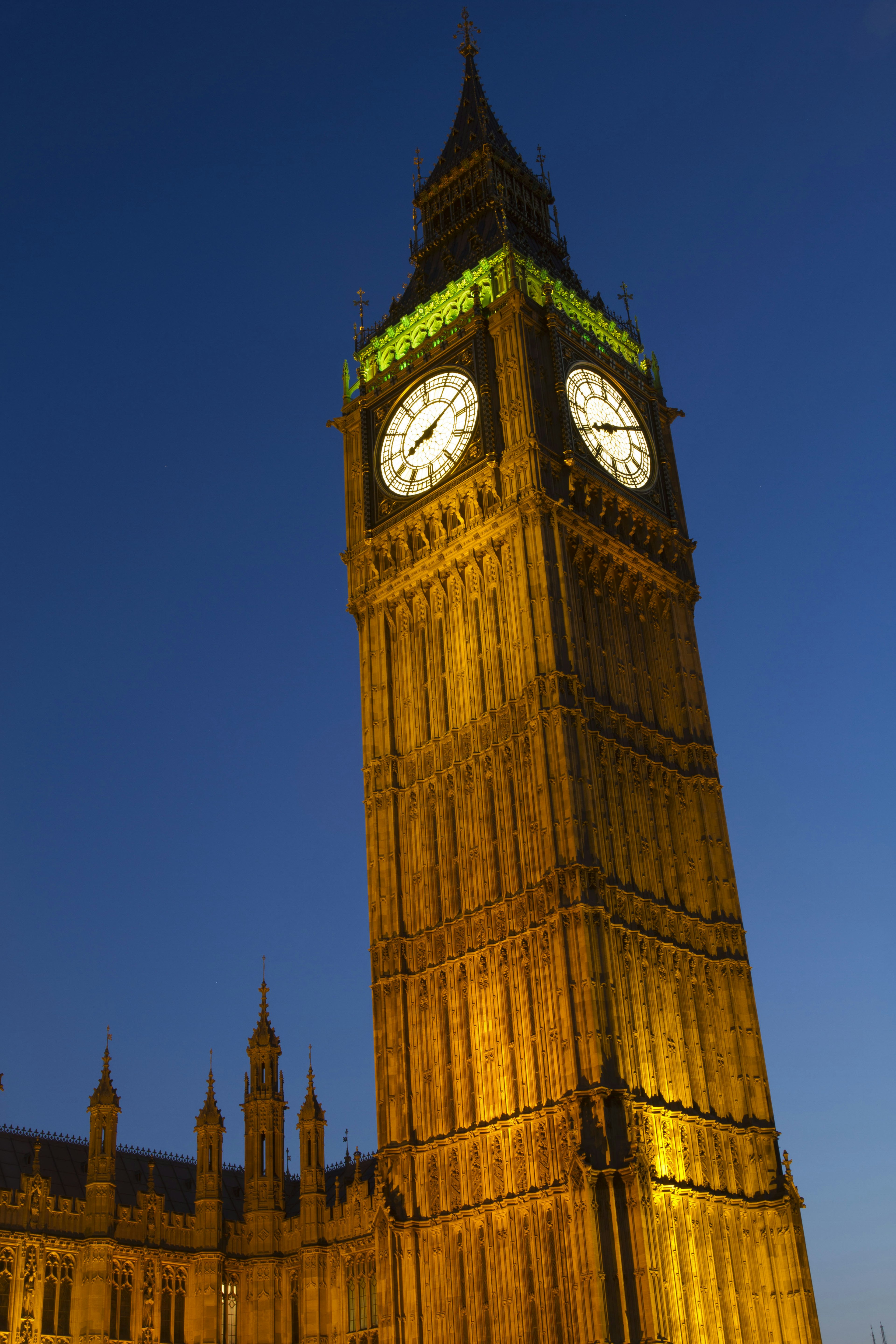 Menara Big Ben yang diterangi di malam hari dengan pencahayaan hijau cerah dan wajah jam besar