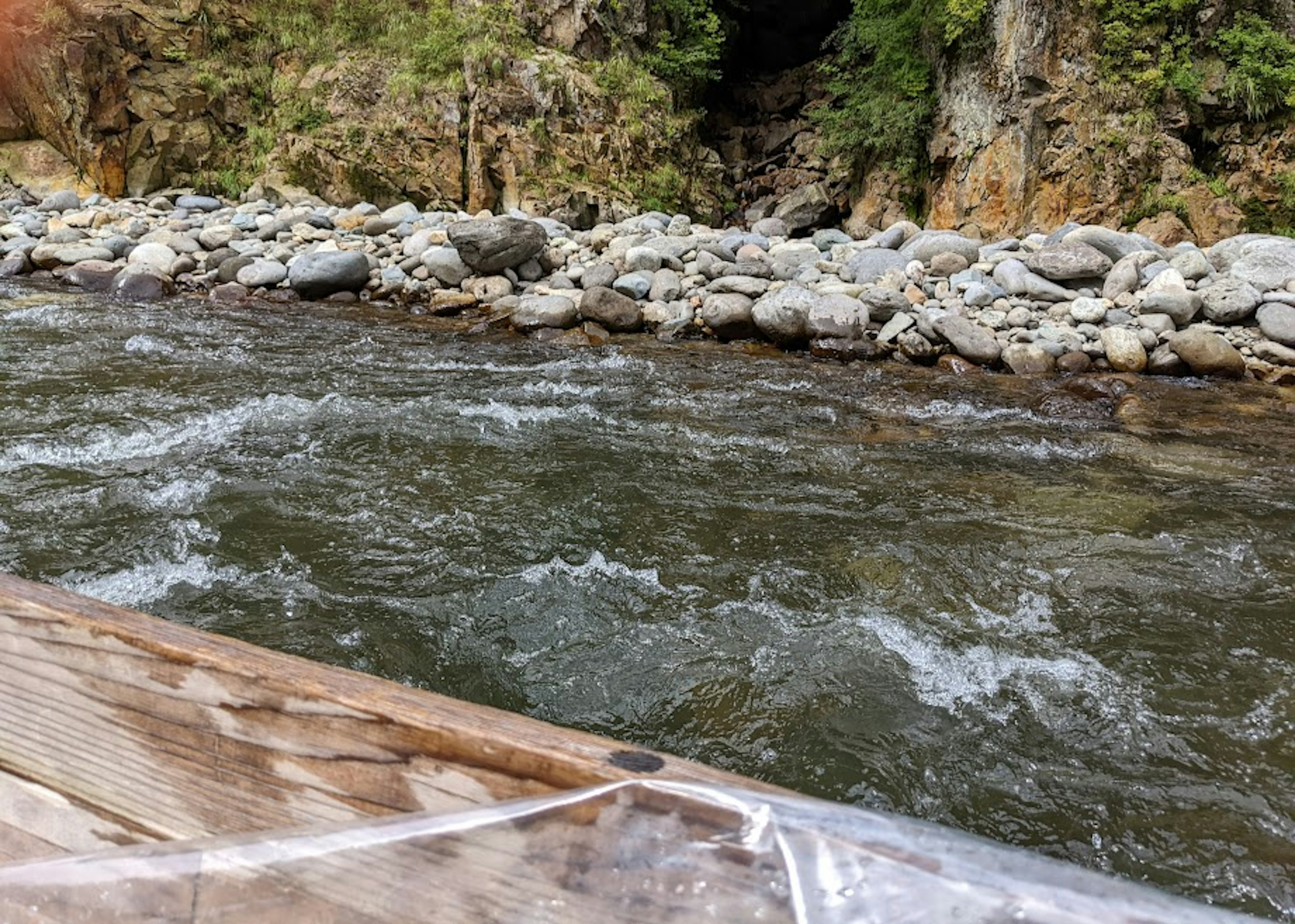 Sungai deras dengan tepi berbatu dan tepi kayu