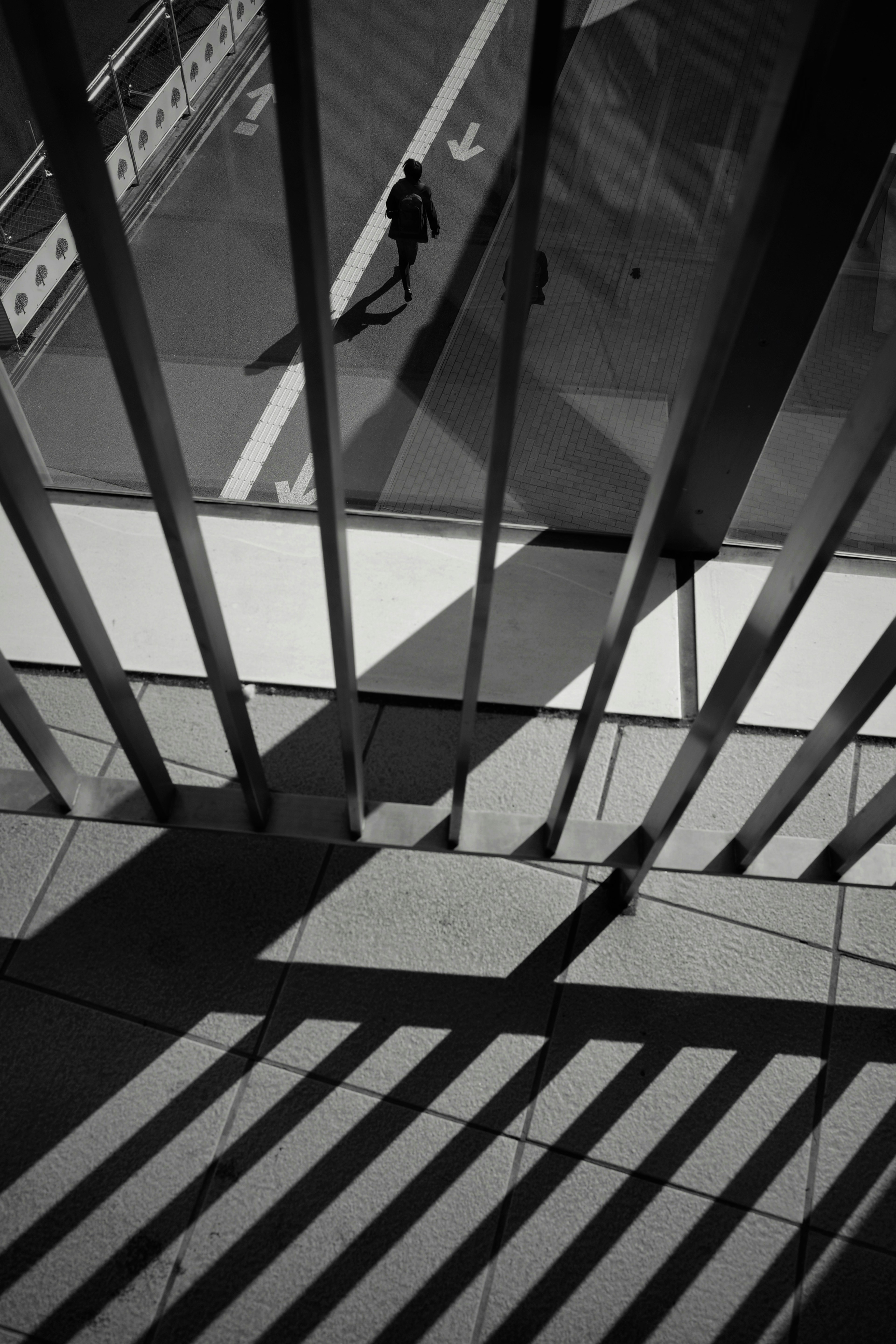 Monochrome photo of shadows and a silhouette seen through stair gaps