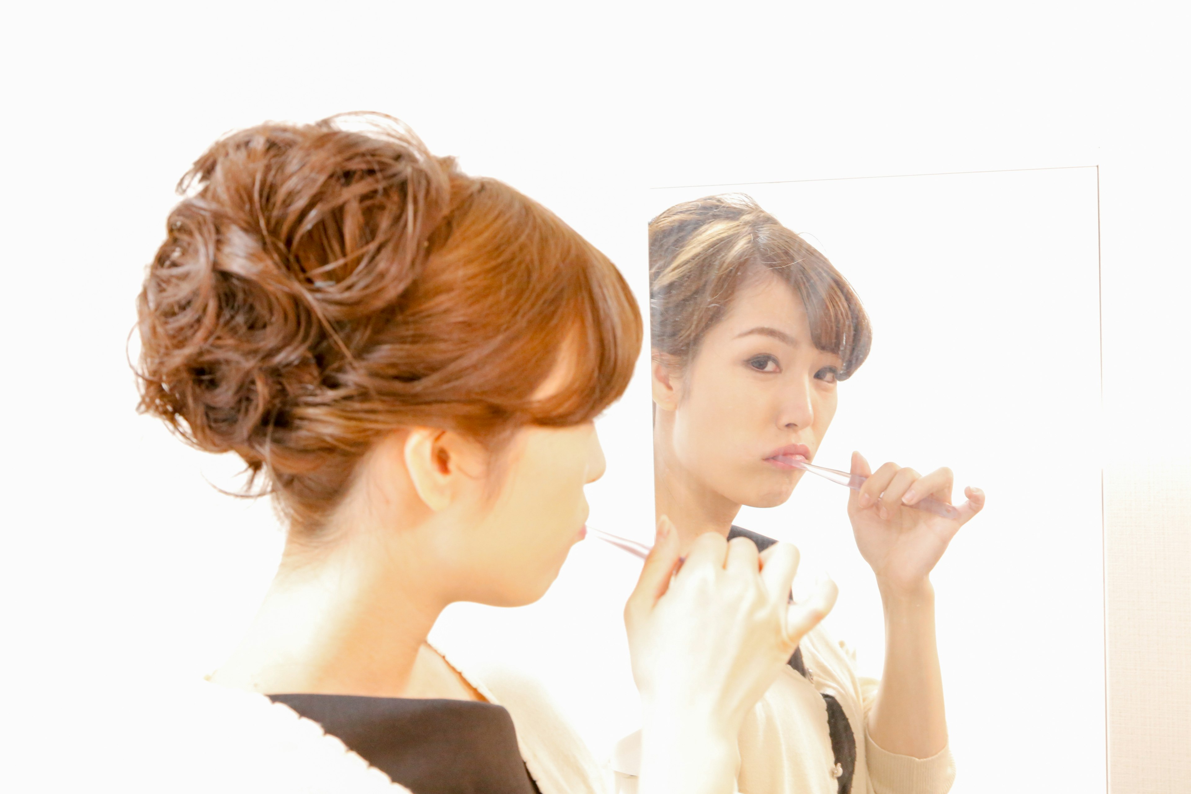 A woman looking at herself in the mirror showing her profile and back view with a soft updo hairstyle