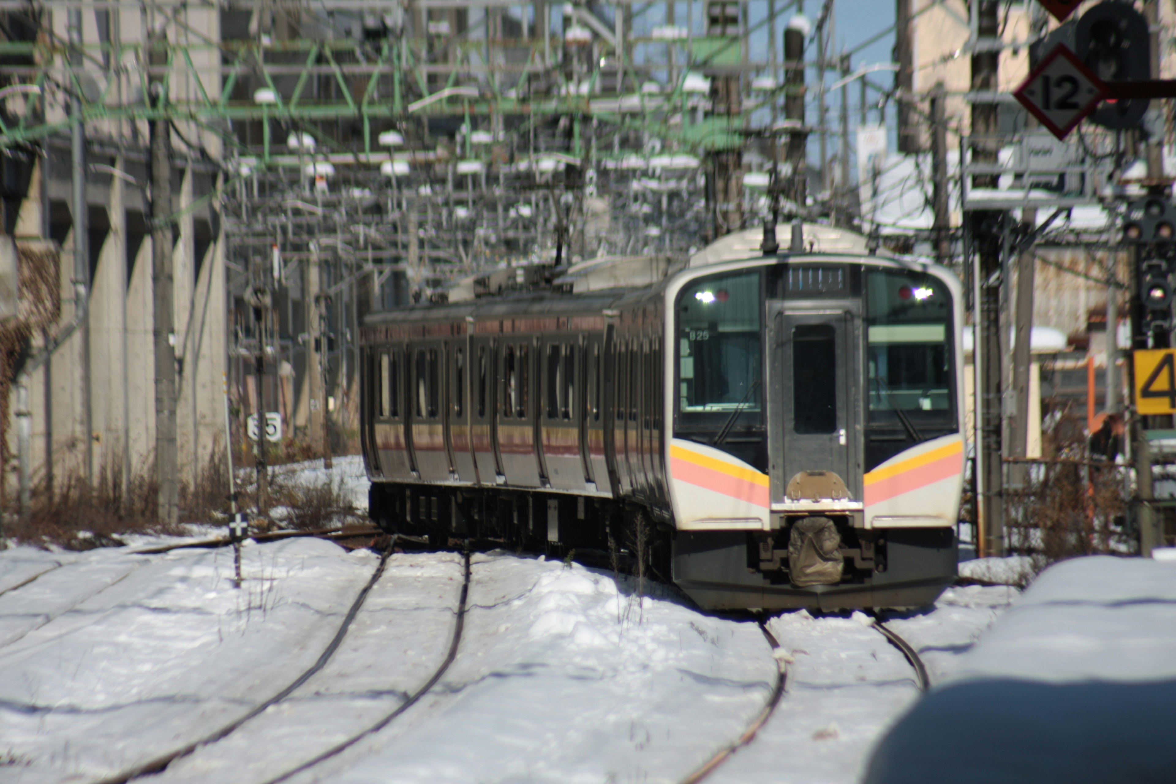 Treno su binari innevati con infrastruttura elettrica circostante