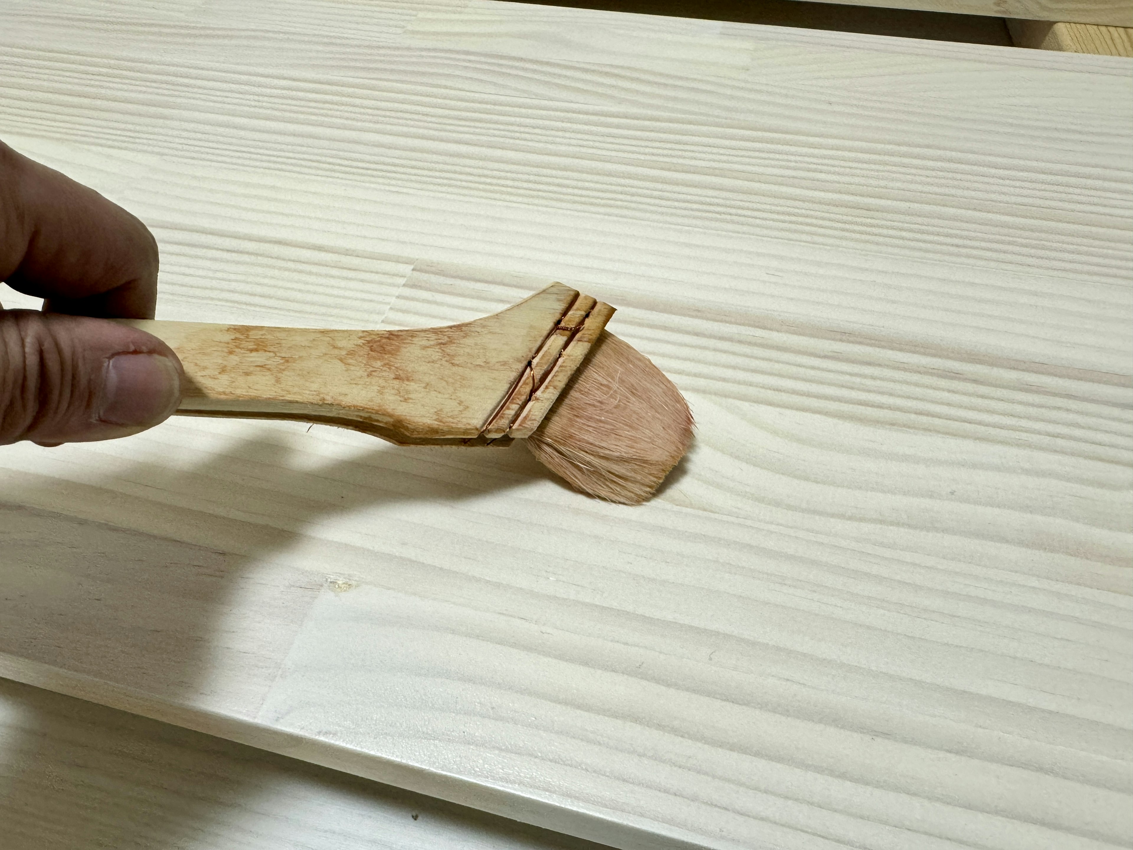 Hand using a wooden tool to smooth the surface of wood