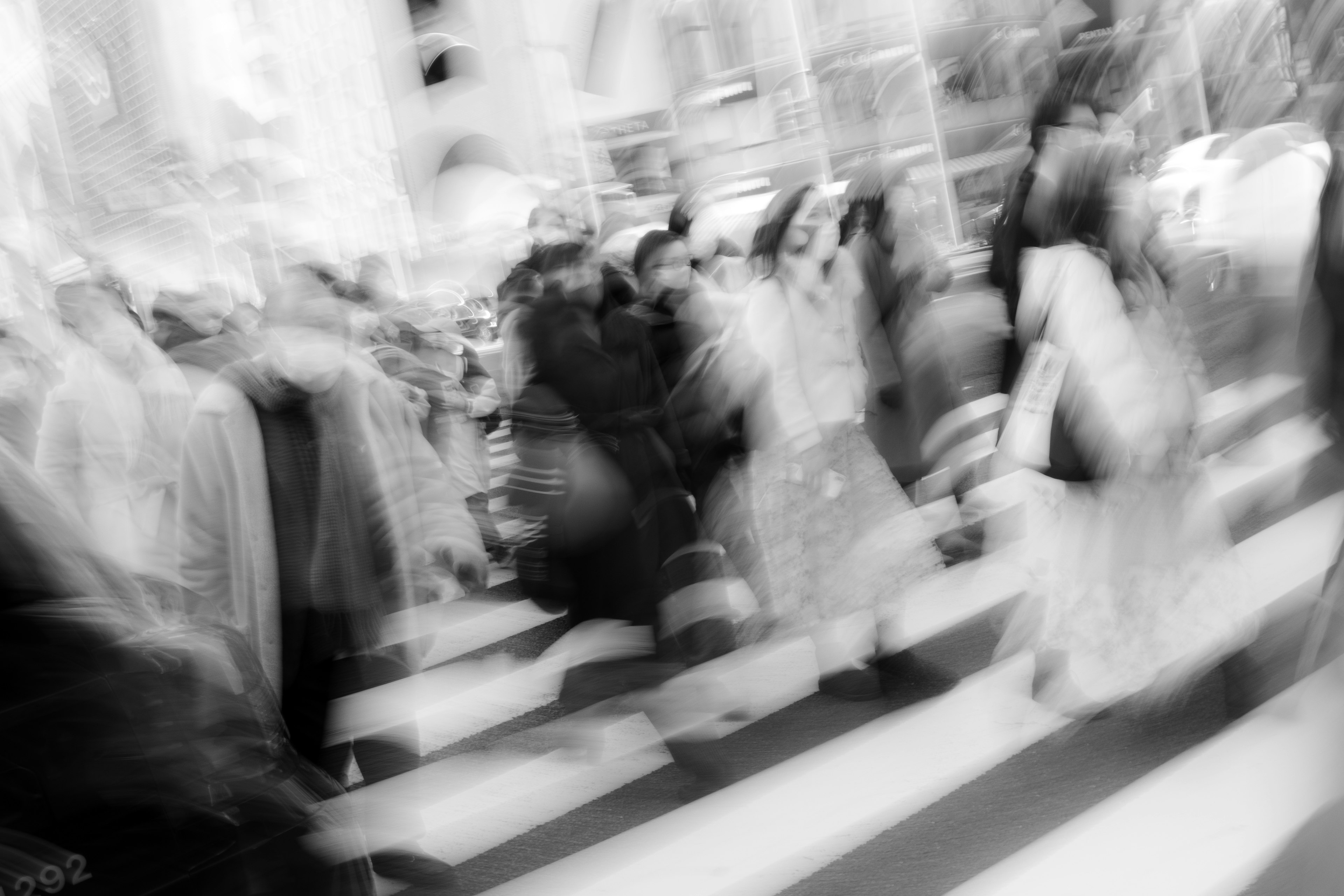 Una escena dinámica de muchas personas cruzando un paso de peatones en blanco y negro