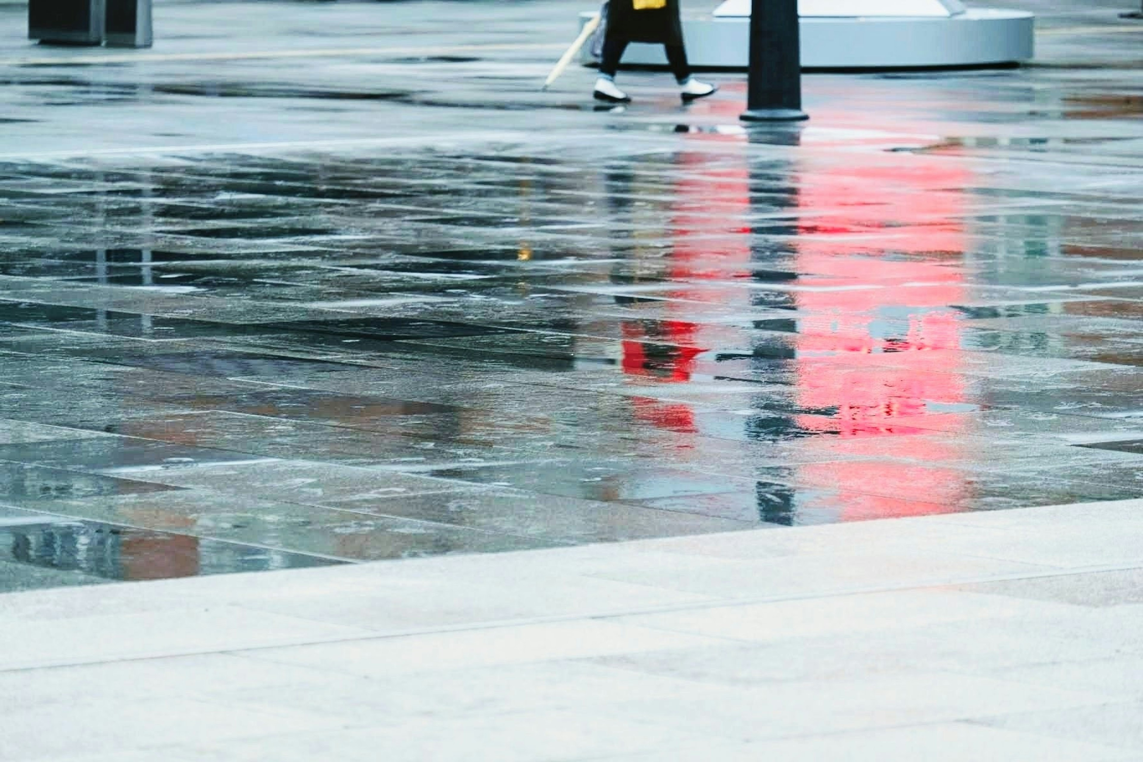 Réflexion de la lumière rouge sur le pavé mouillé avec une personne marchant