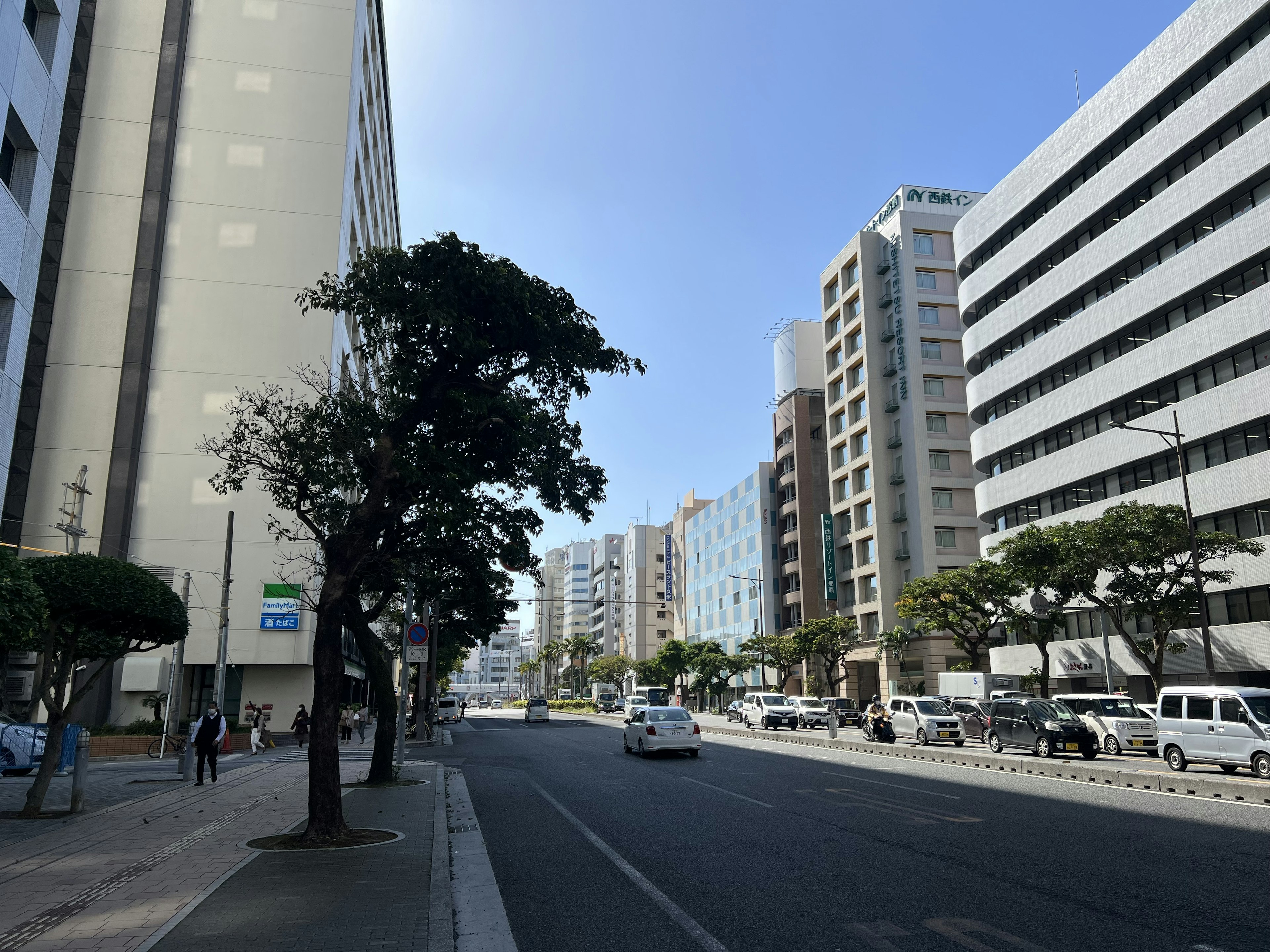 Urban street lined with high-rise buildings and clear blue sky