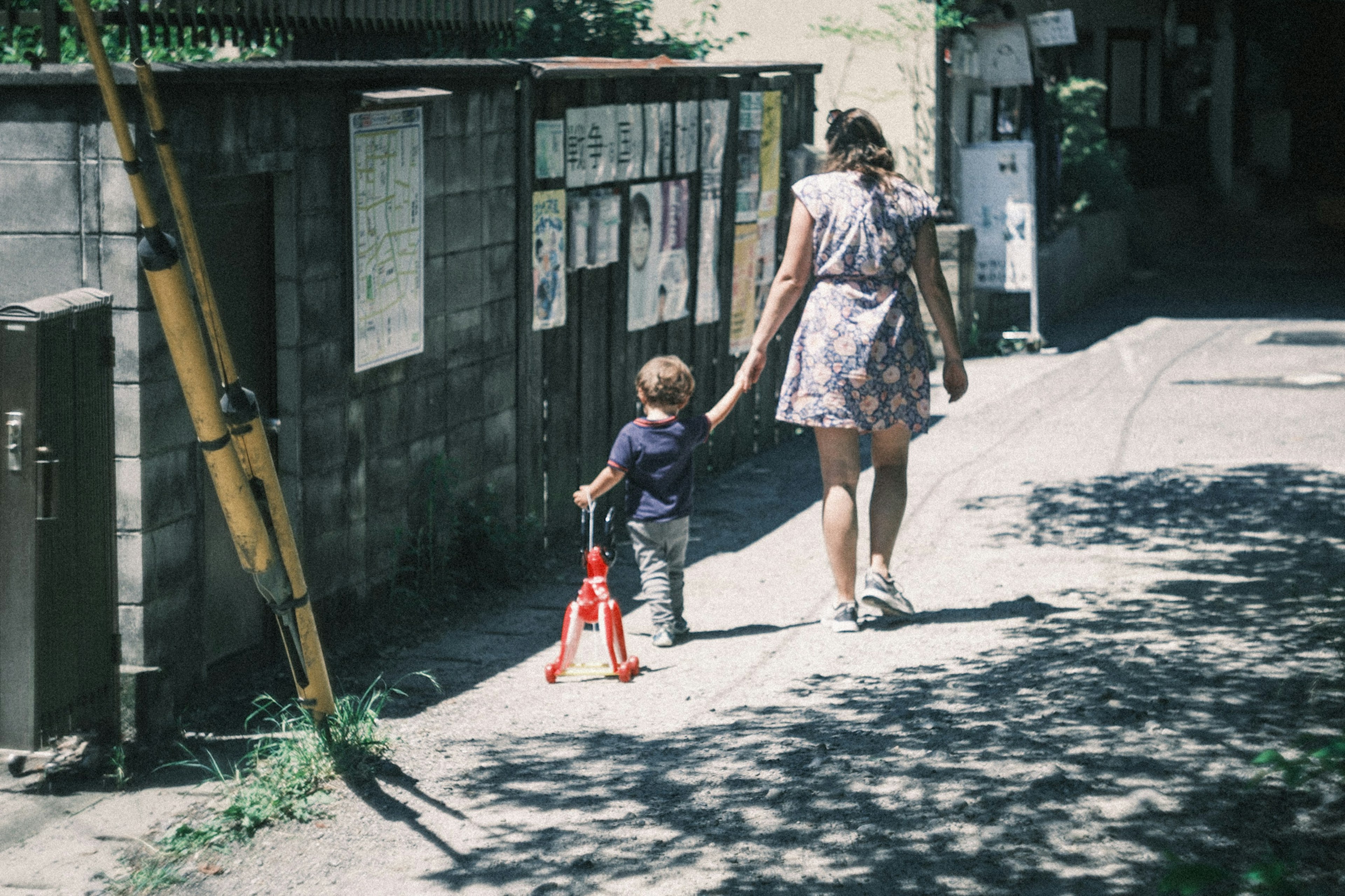 Mujer caminando con un niño de la mano en una calle soleada