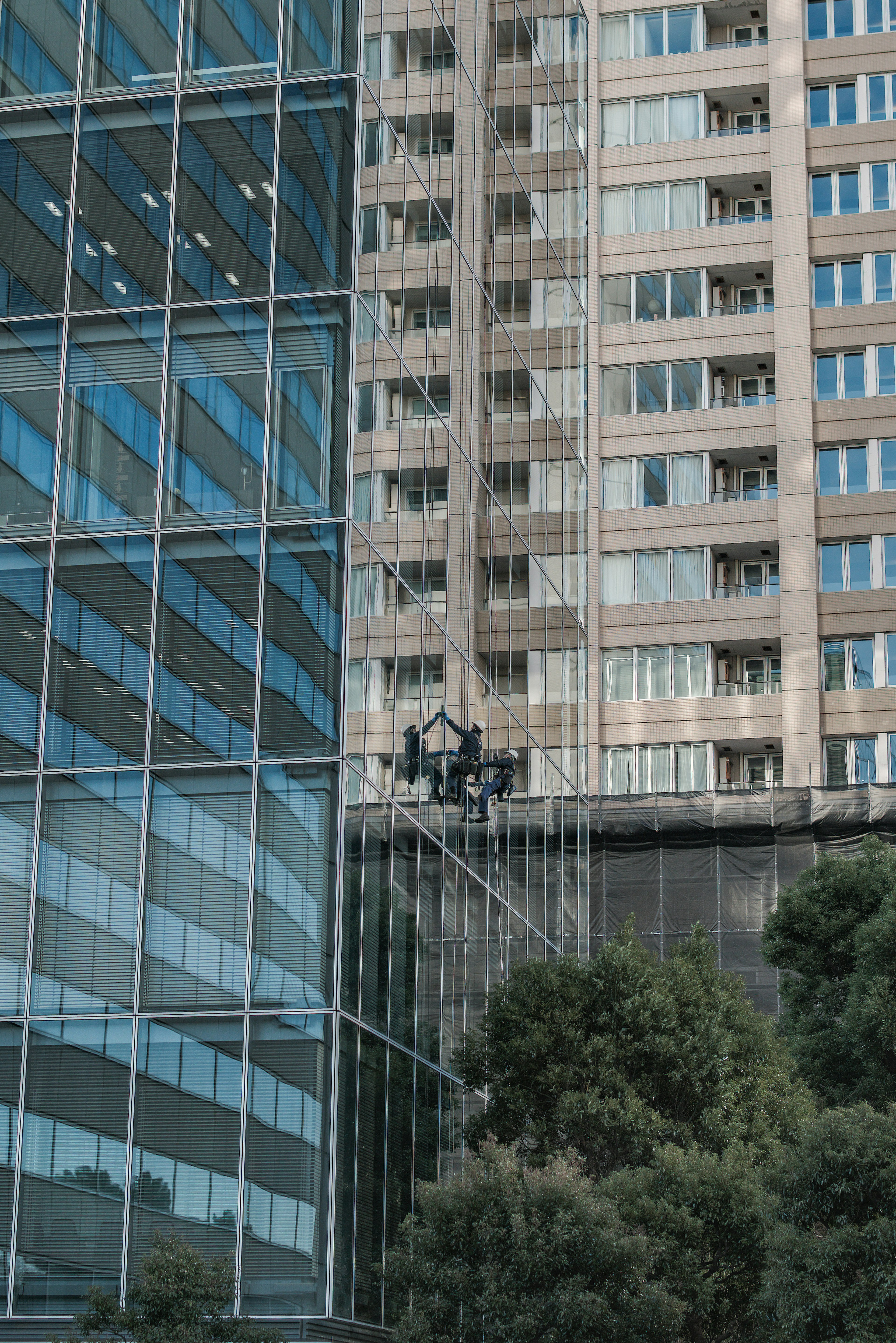 Facciata in vetro di un edificio moderno accanto a una struttura residenziale alta