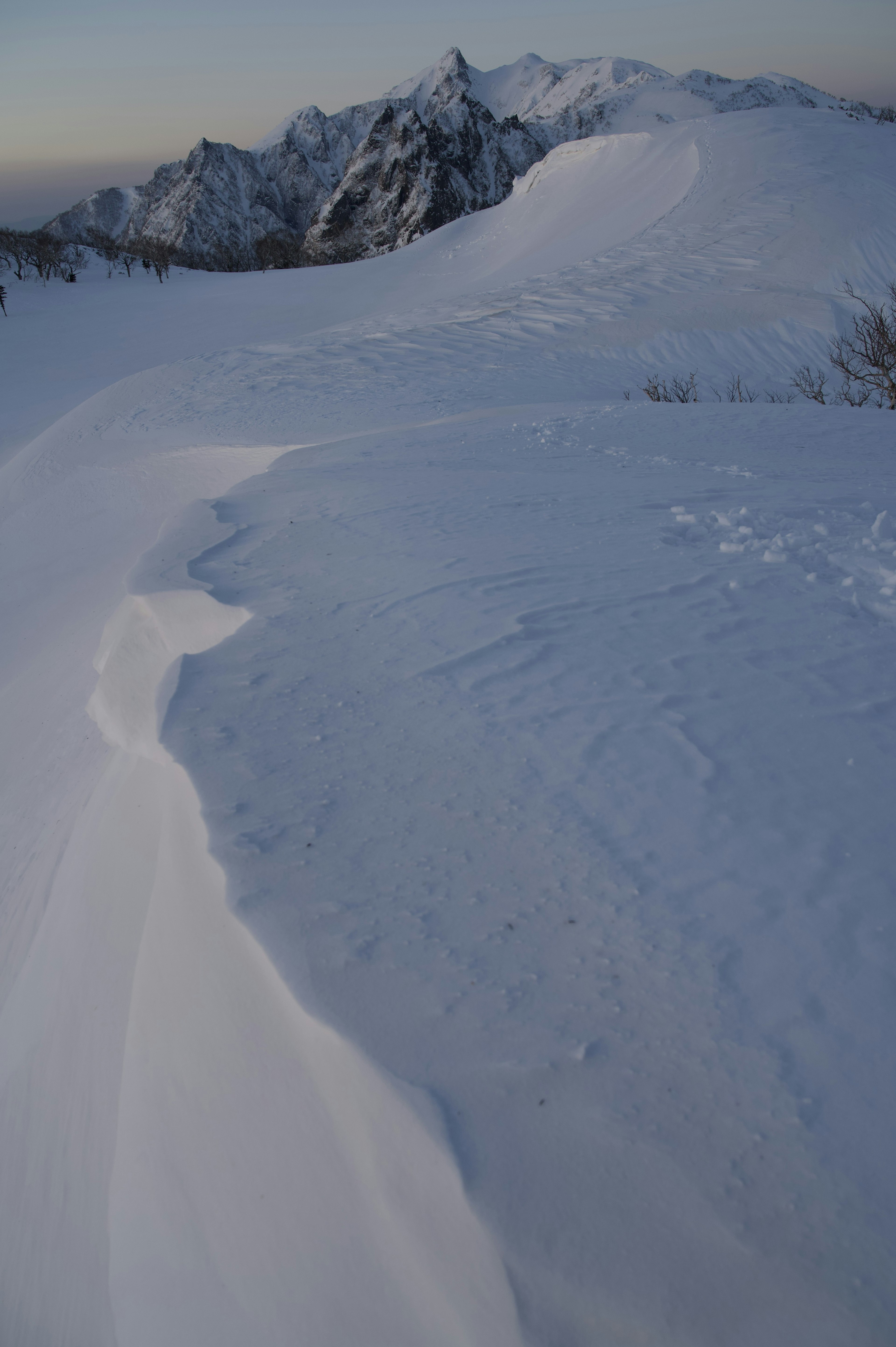 Paisaje montañoso cubierto de nieve con curvas de nieve suaves