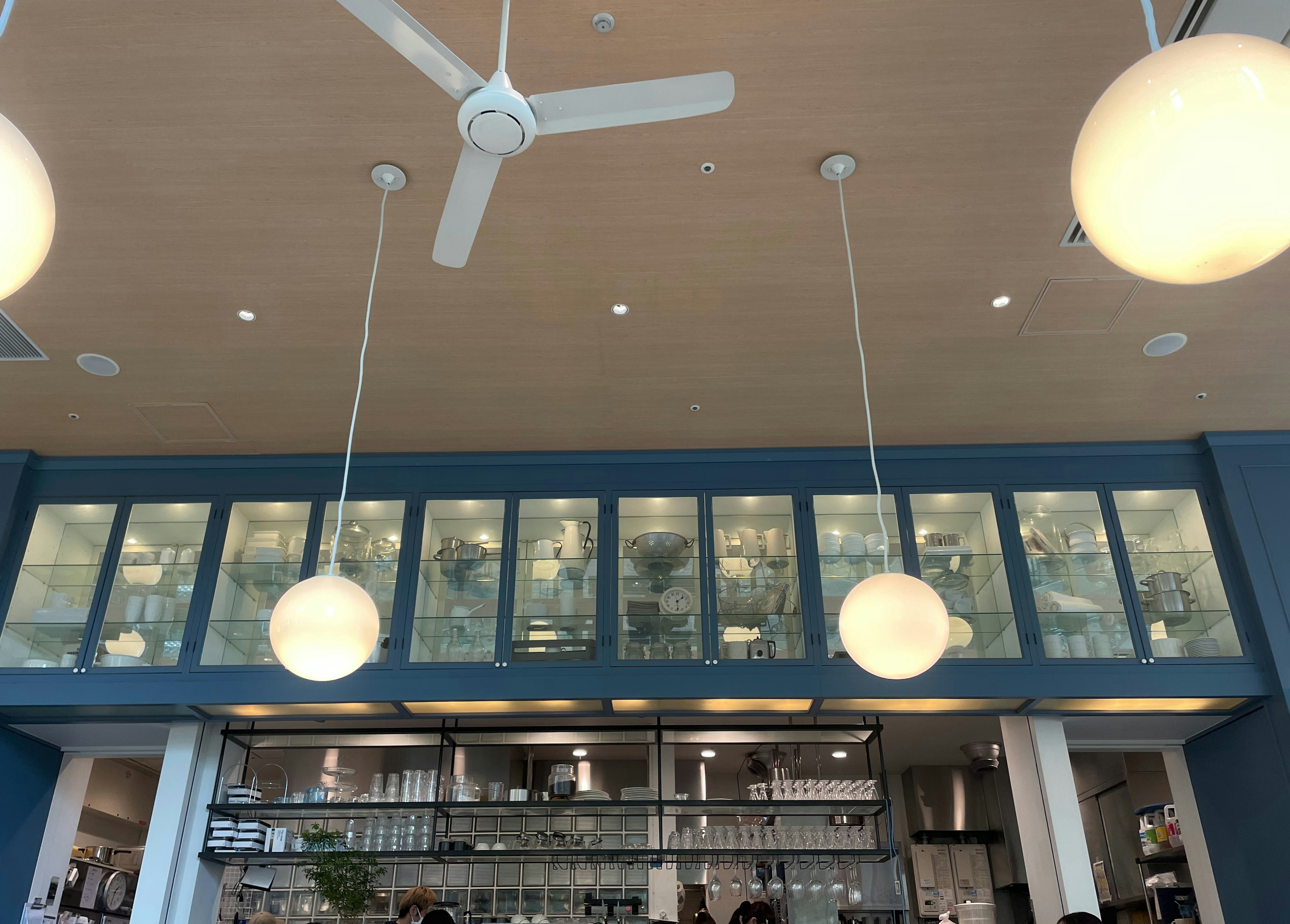 Interior view of a cafe featuring hanging lights and a ceiling fan against blue walls