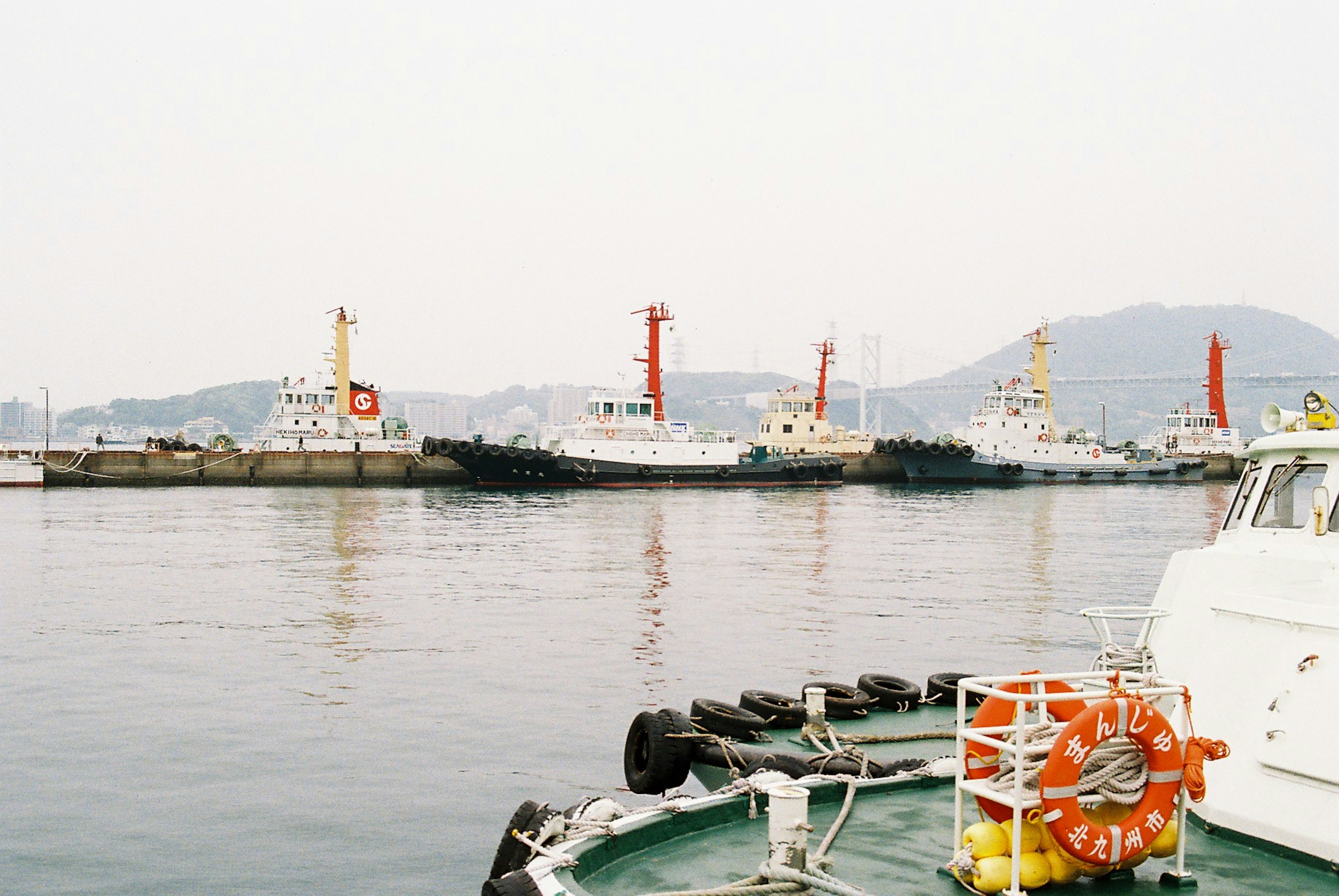 Multiple tugboats docked at the harbor with calm water