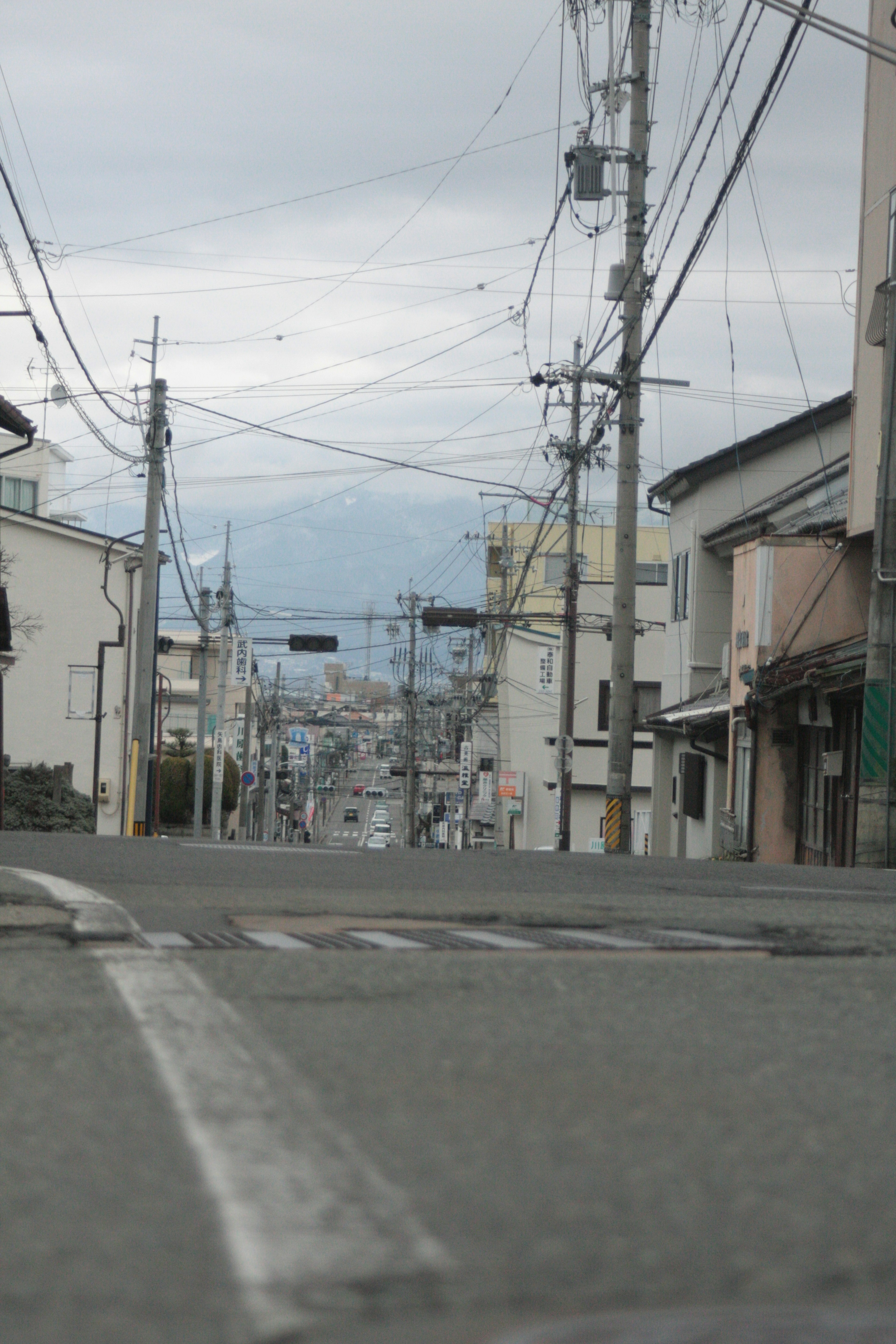 静かな街の風景、曇り空、電線が交差する通り