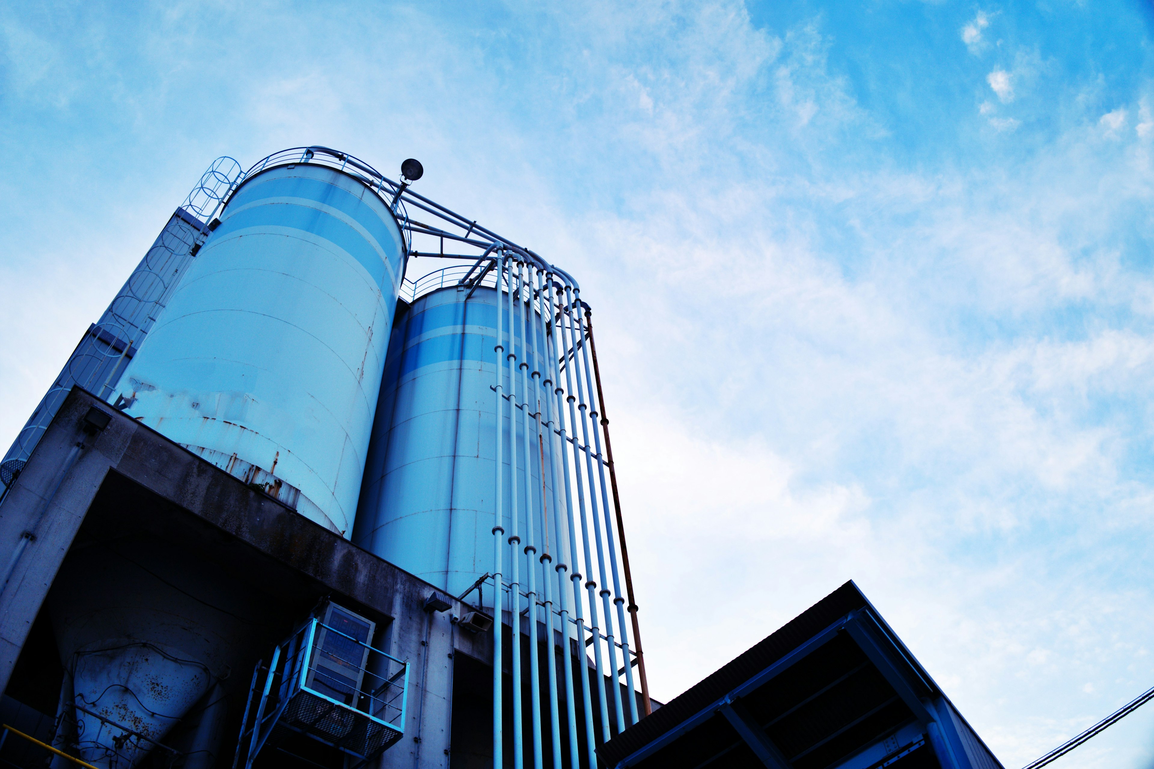 Two industrial silos silhouetted against a blue sky