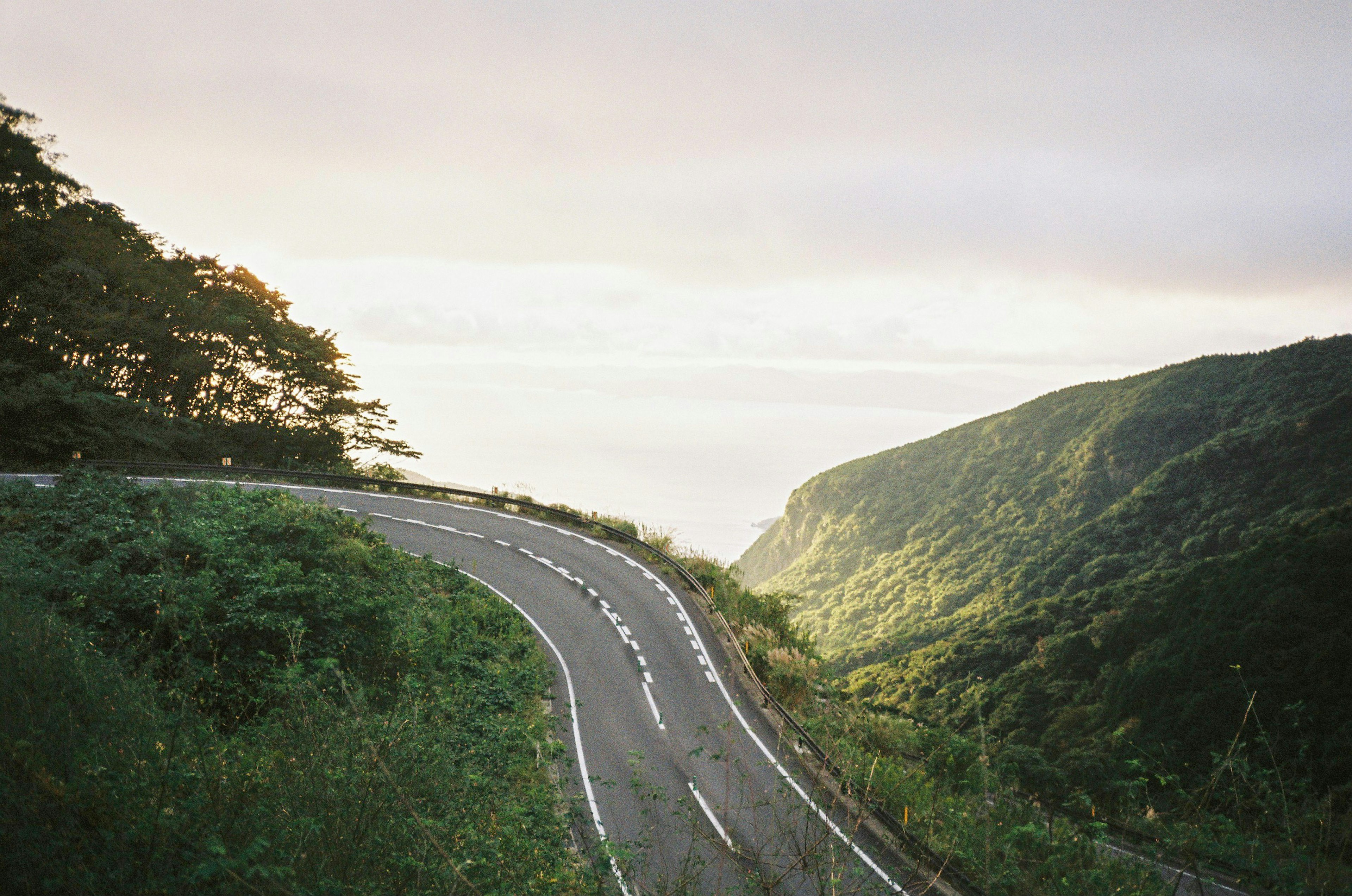 Winding road surrounded by green hills and a serene sky