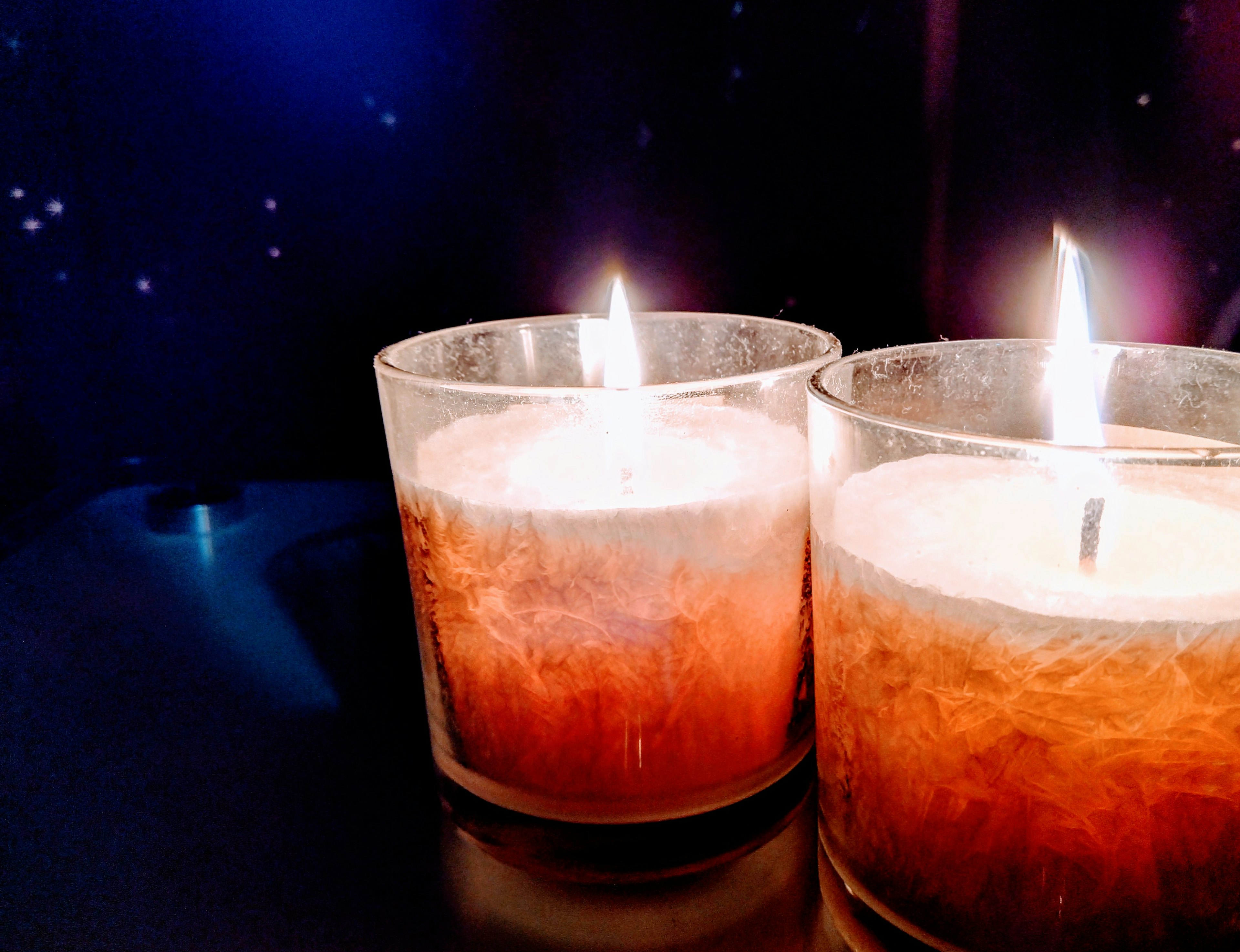 Image of candles in glass holders with flickering flames against a starry background