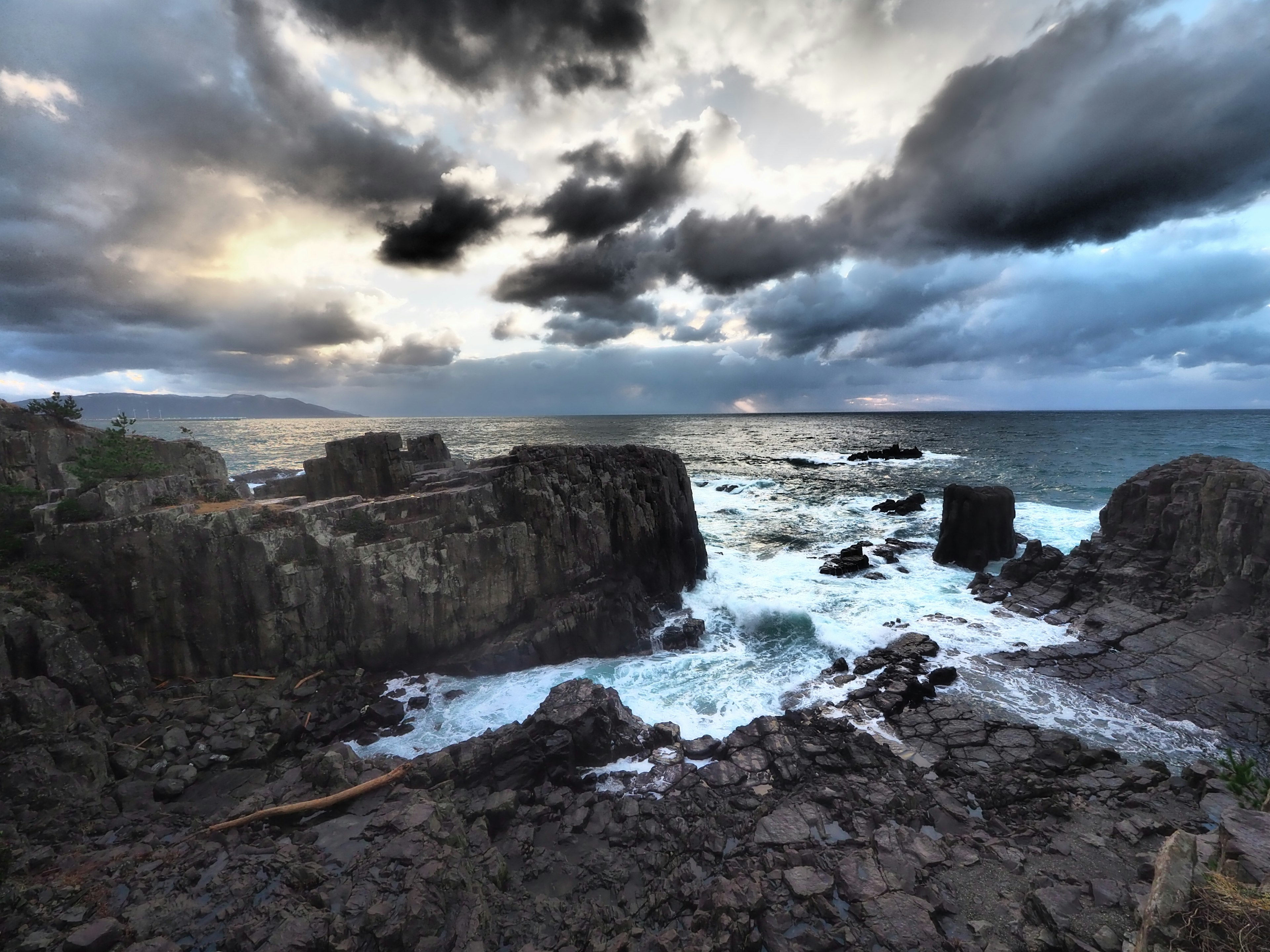 Paisaje costero con rocas y olas rompiendo bajo un cielo nublado