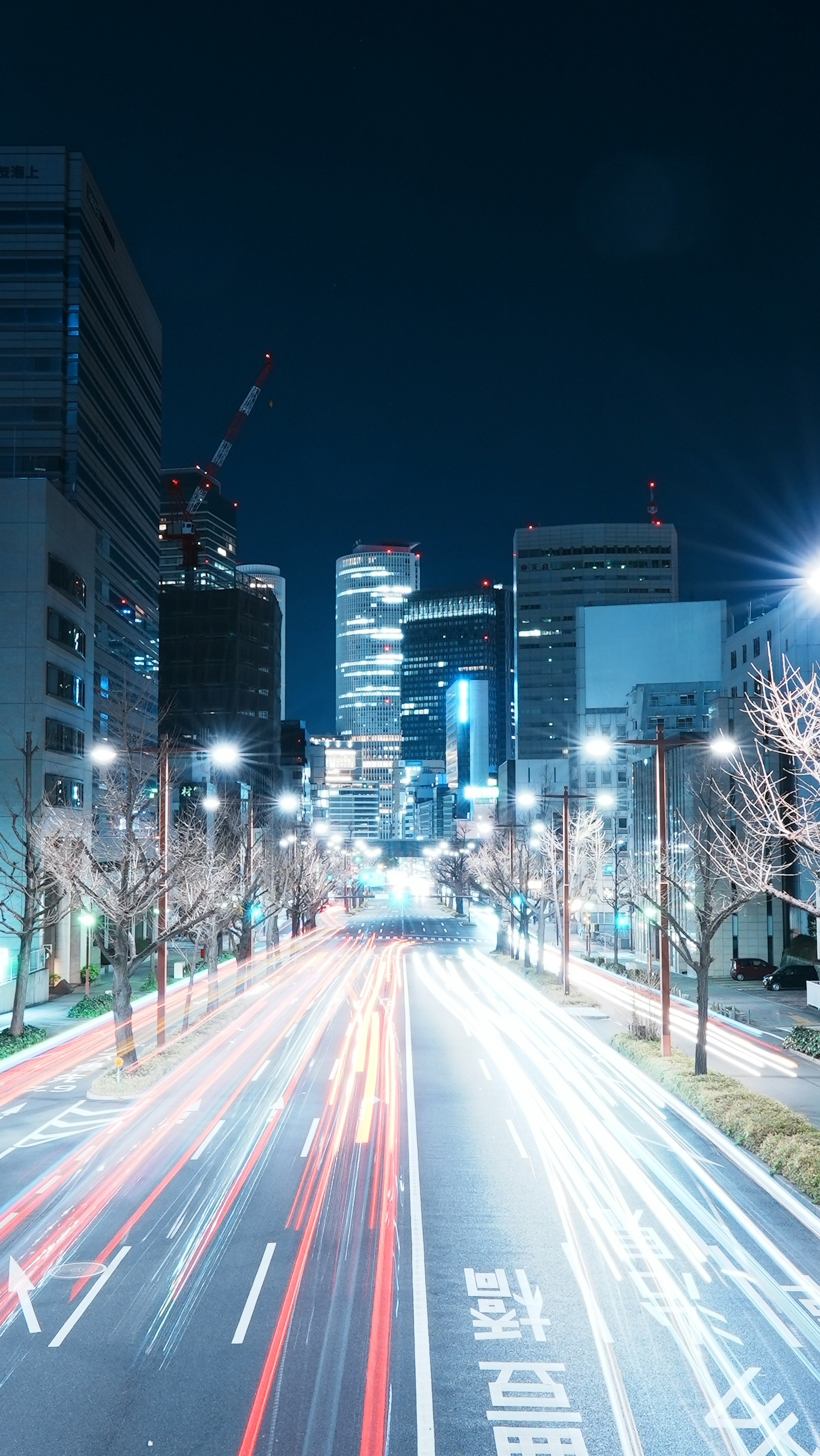 Paisaje urbano nocturno con rascacielos iluminados y luces de coches en movimiento