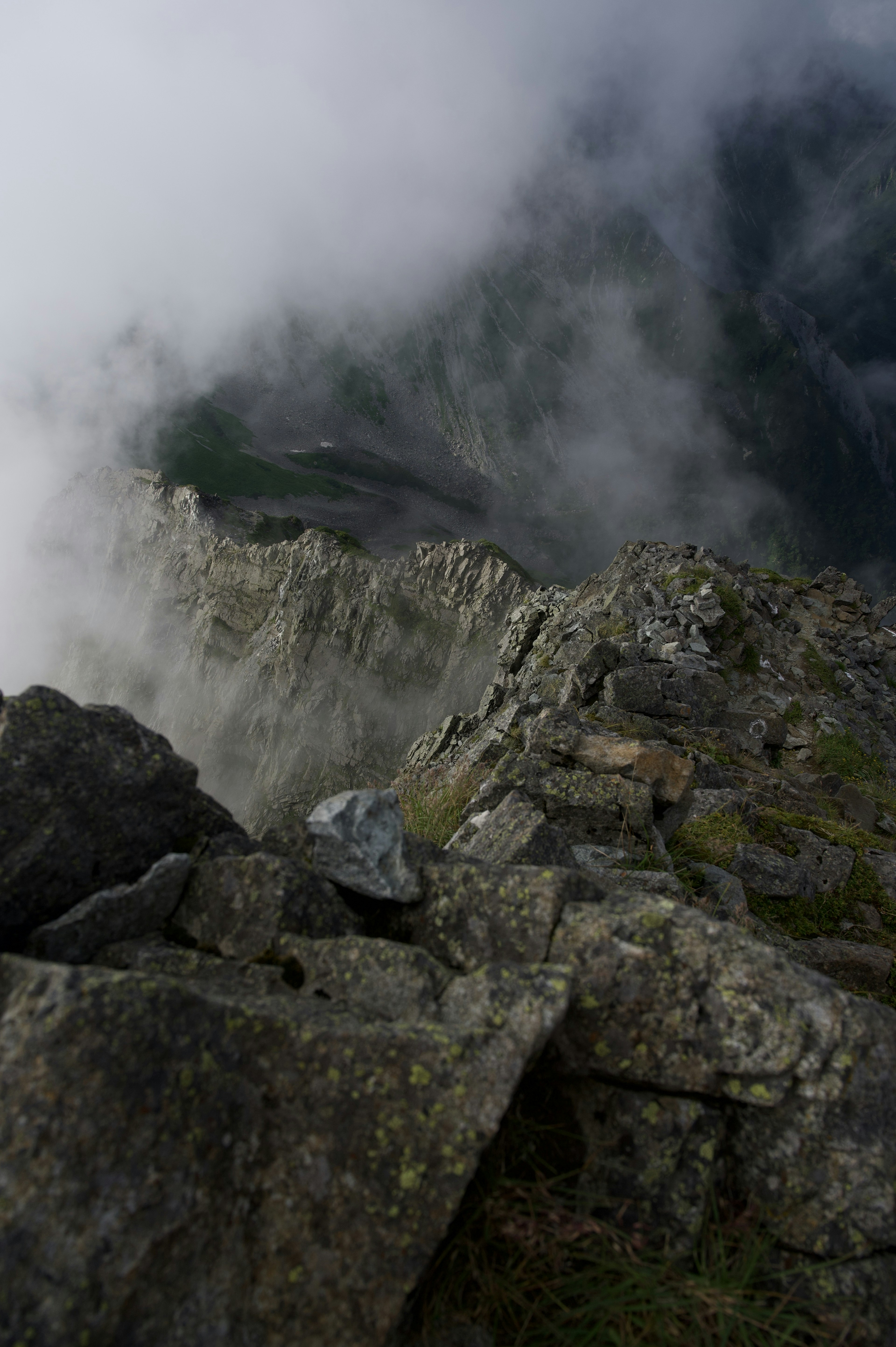 Vue panoramique d'une falaise montagneuse couverte de brouillard avec des rochers et de l'herbe verte