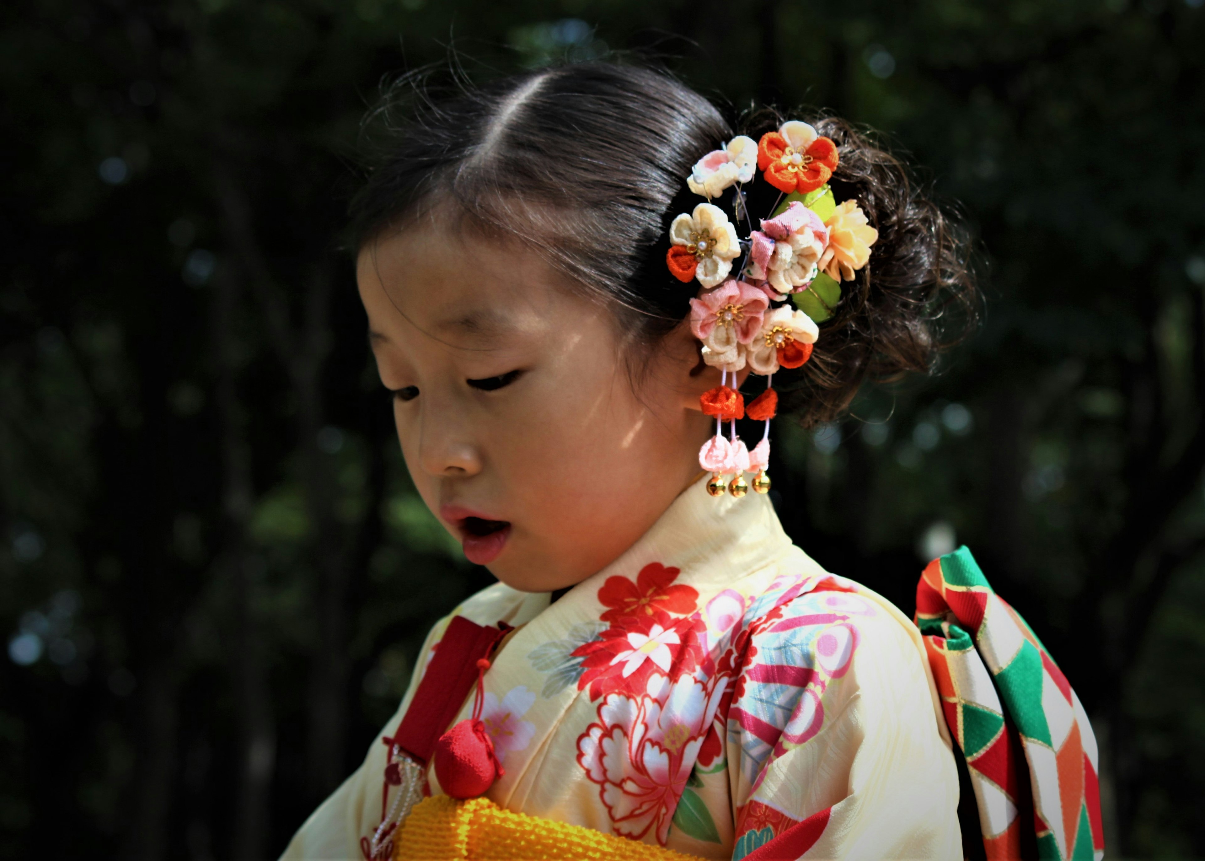 Bambina in kimono giapponese tradizionale con accessori floreali nei capelli