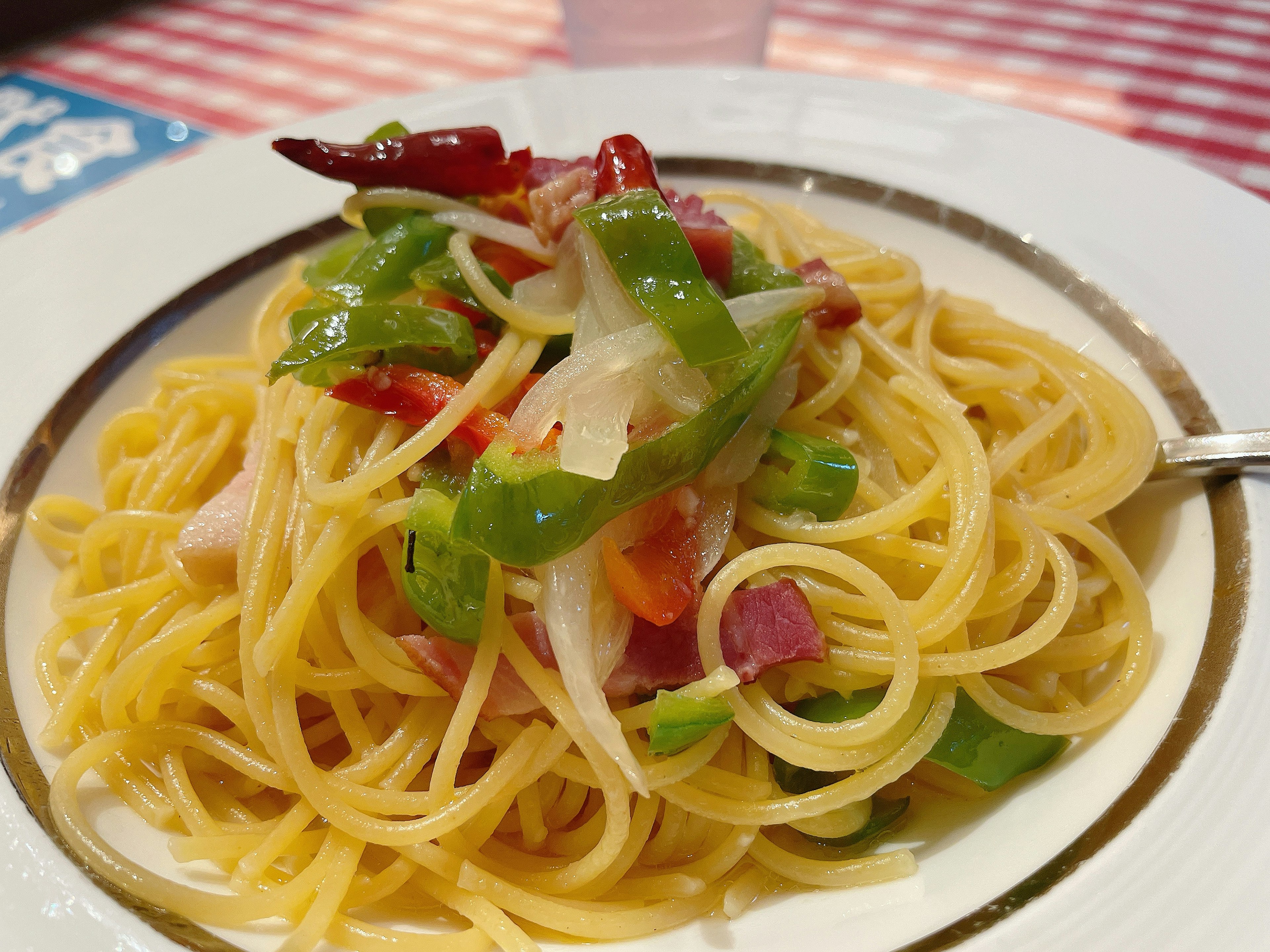 Plate of spaghetti topped with green and red vegetables