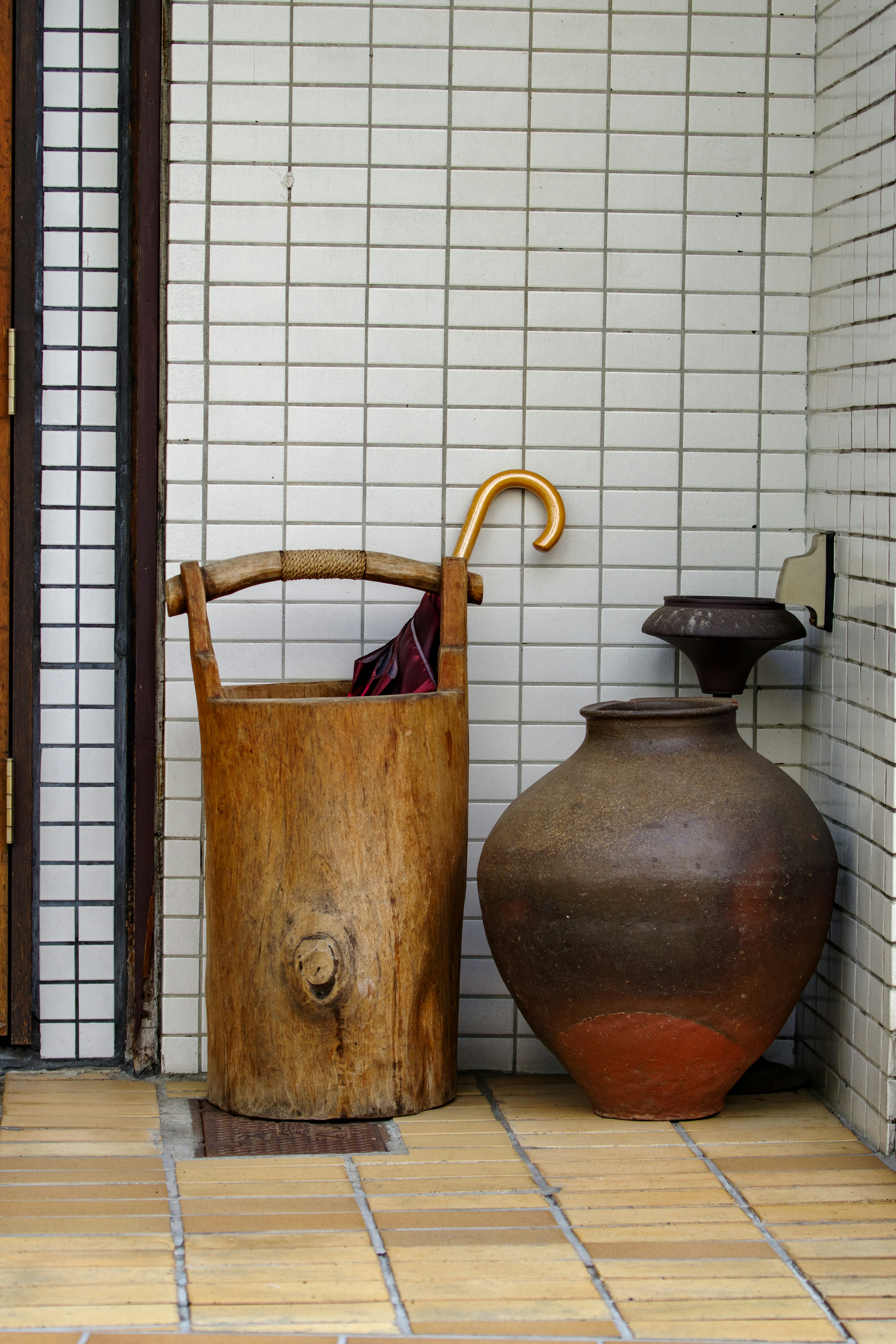 Wooden umbrella stand and ceramic jar in a hallway