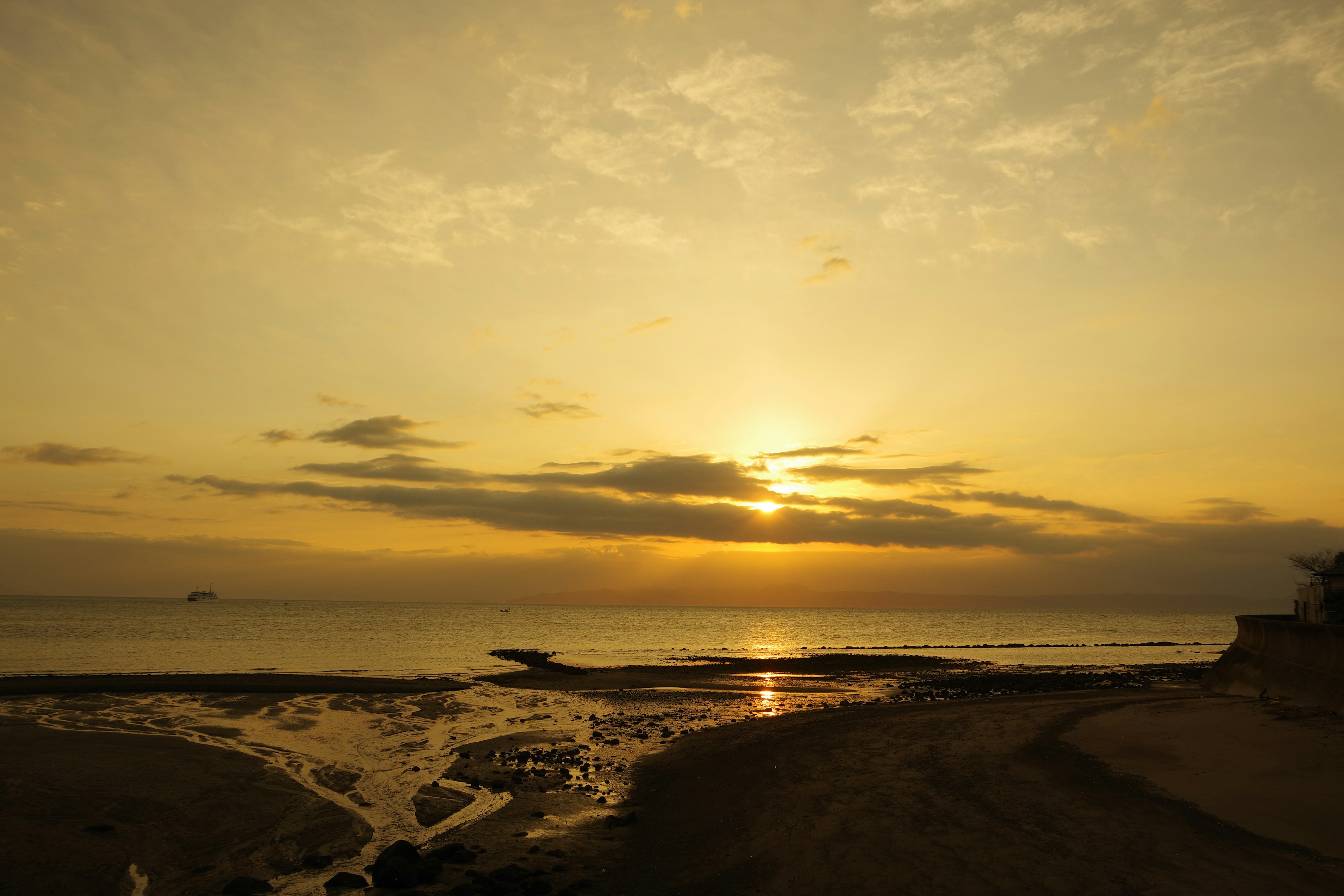 ทิวทัศน์พระอาทิตย์ตกที่สวยงามเหนือชายหาดพร้อมกับเมฆนุ่มและน้ำที่สงบ