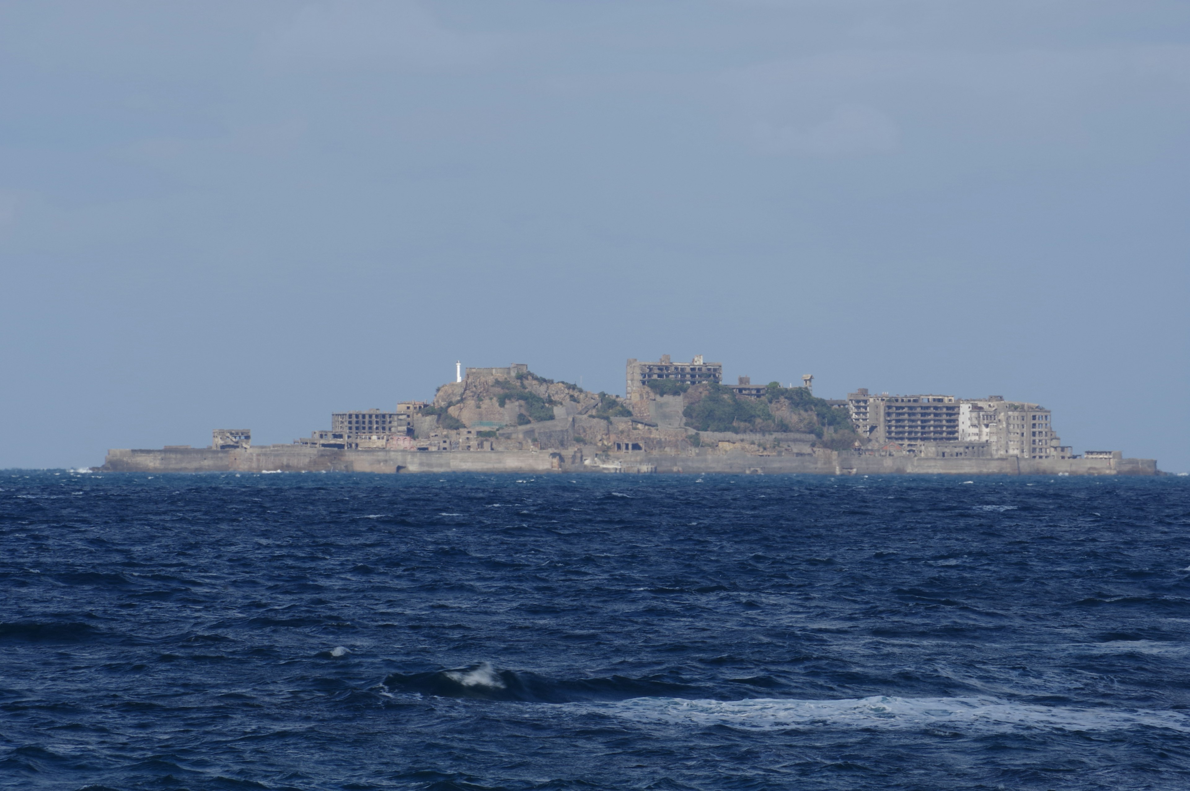 A deserted island in the ocean with visible ruins and striking blue waters