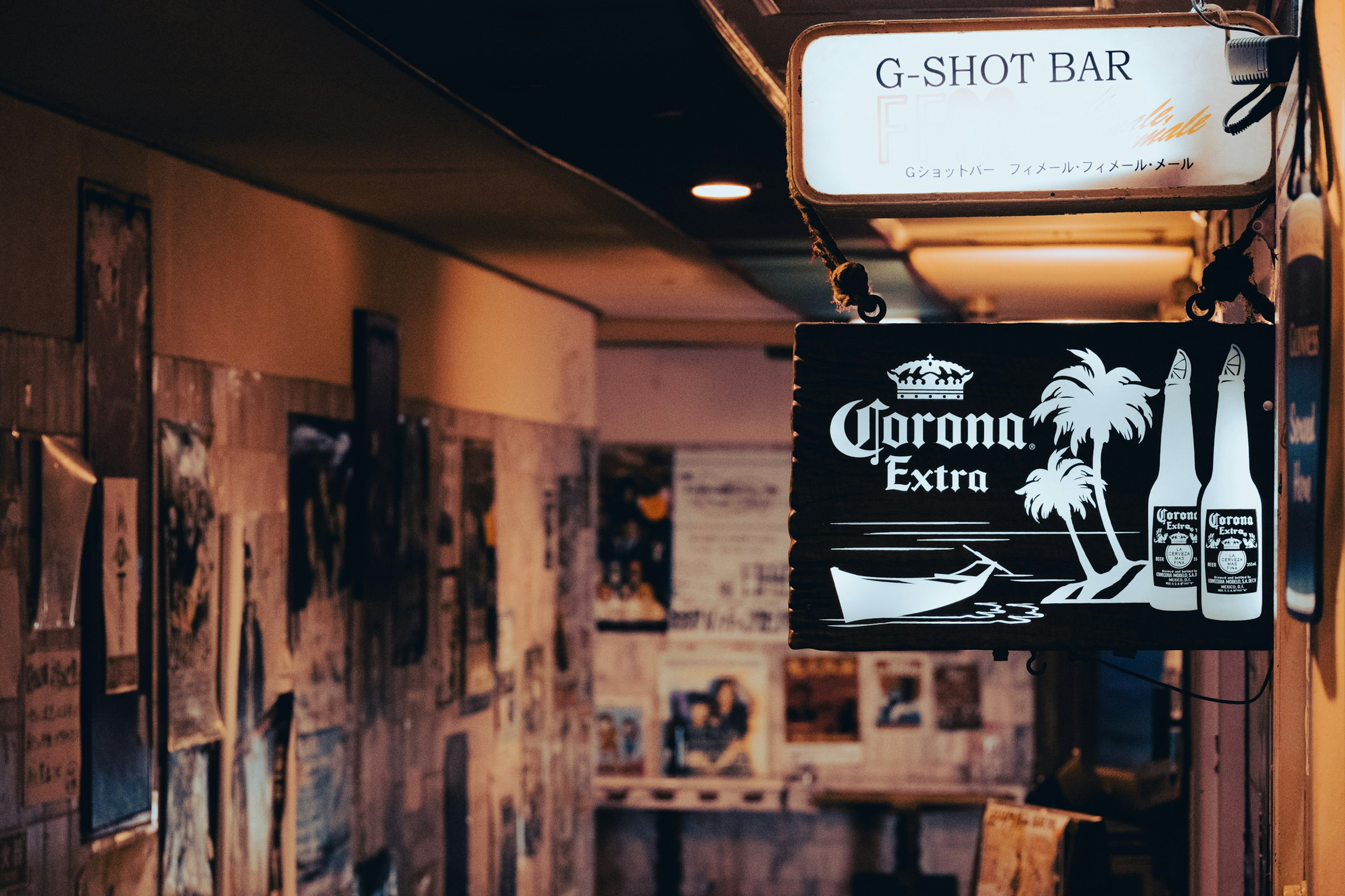 Couloir étroit avec un panneau G Shot Bar et un panneau néon Corona Extra